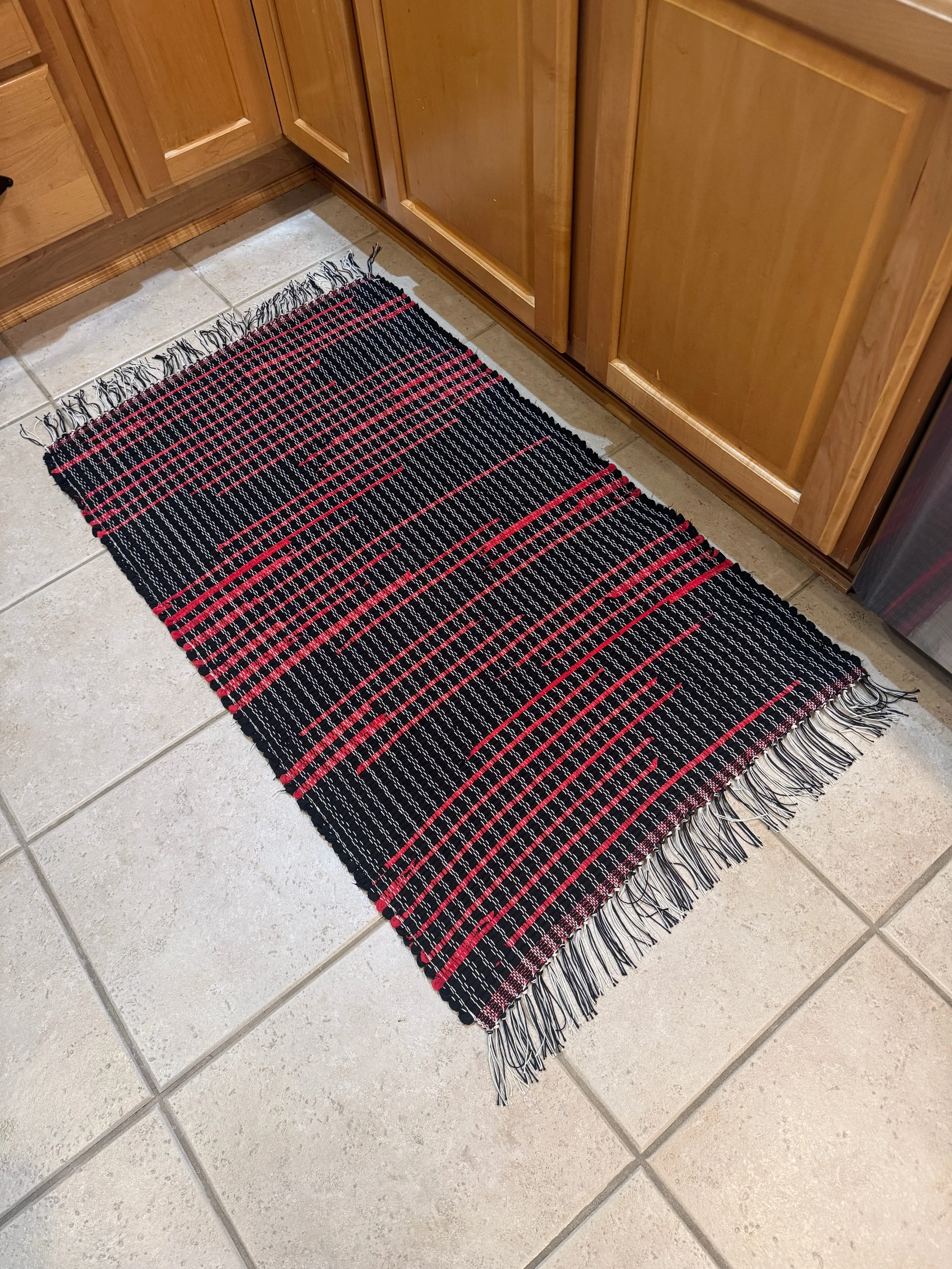Handmade black and red rag rug displayed in kitchen showing full pattern