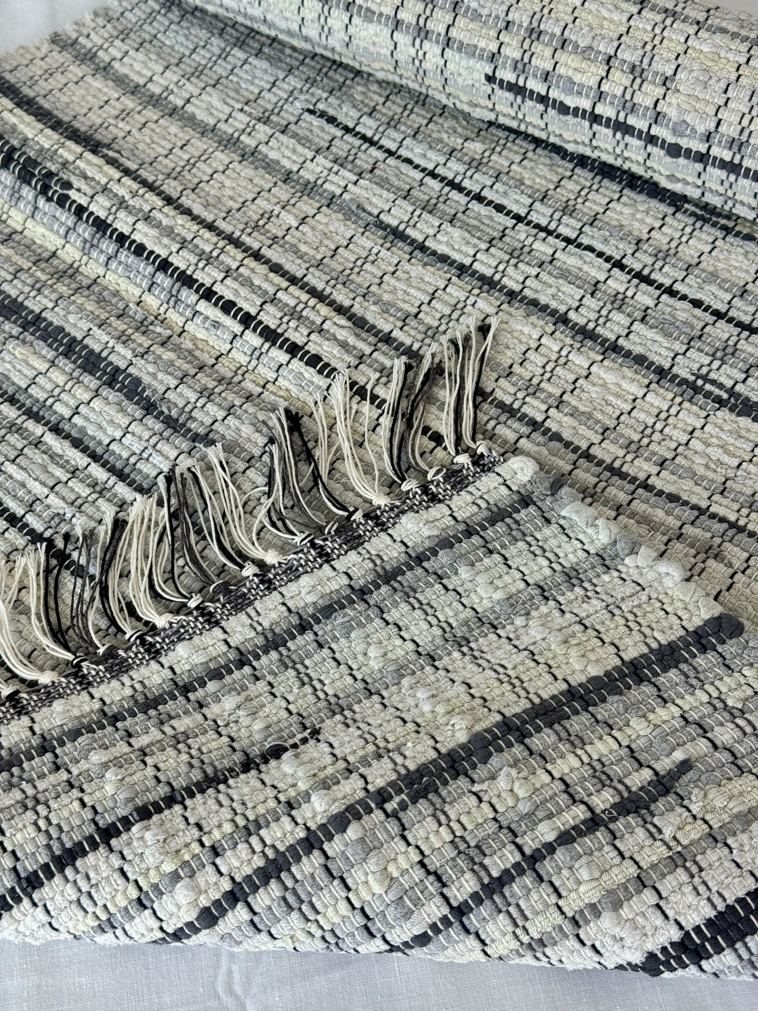 Folded handmade rug showing reverse side and fringe