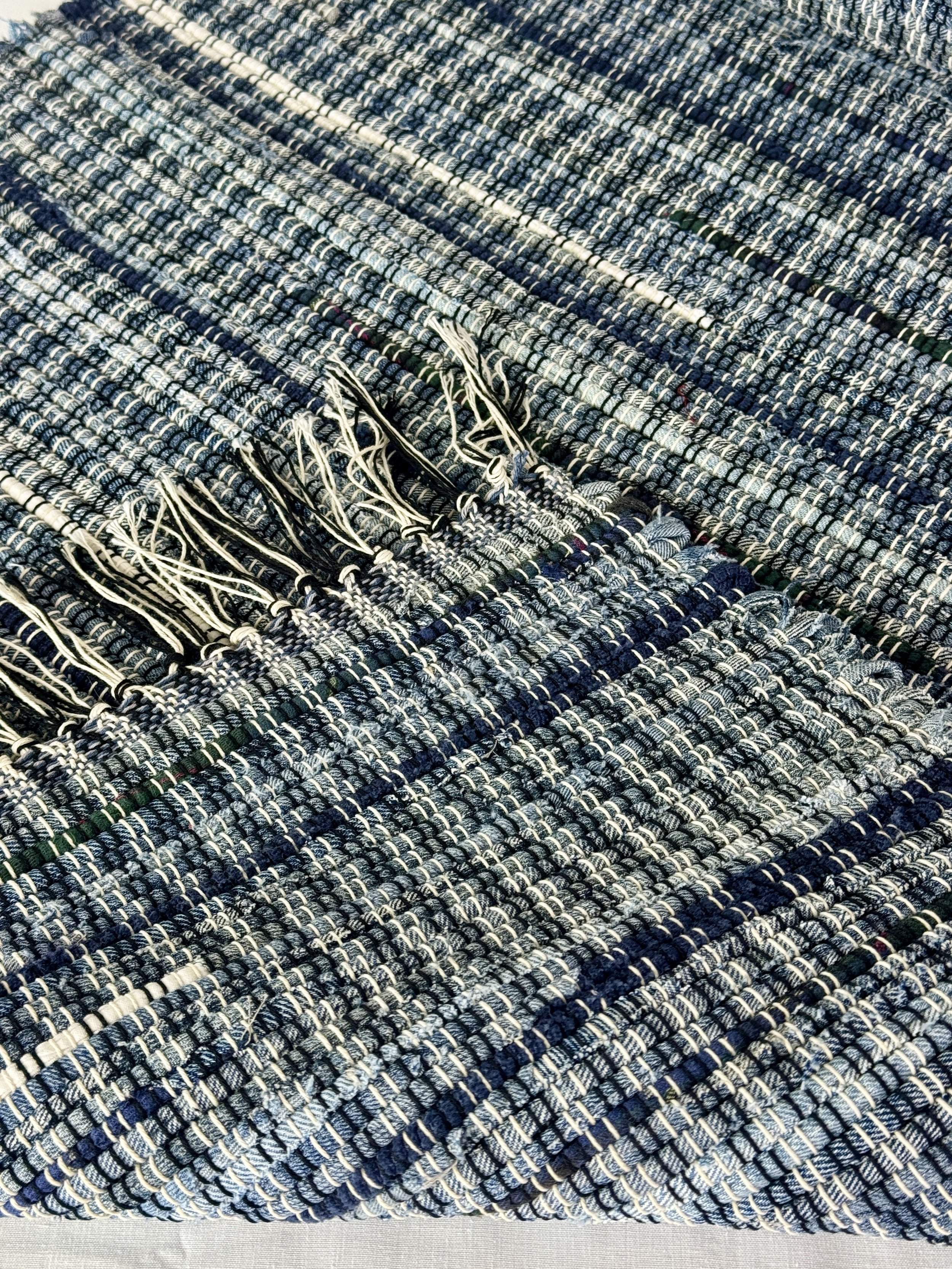 Folded handmade rug showing reverse side and fringe