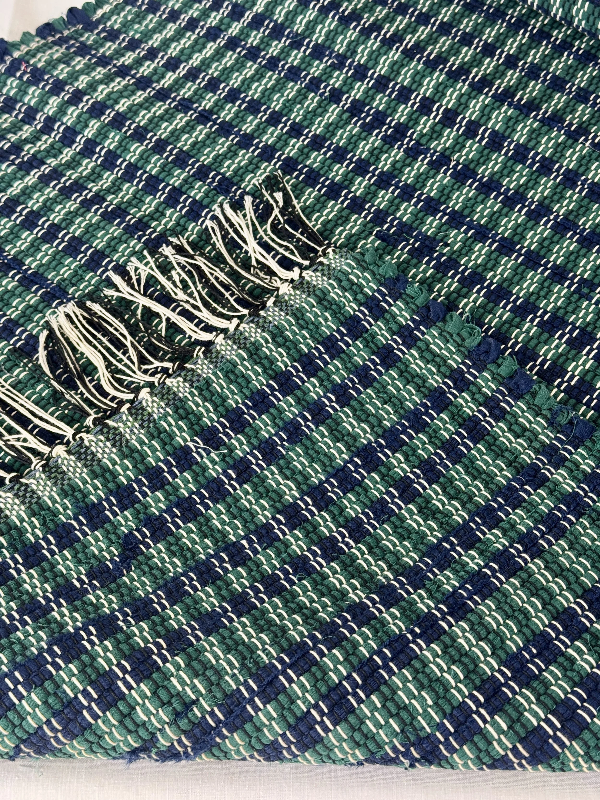 Folded handwoven rag rug showing reverse side and fringe