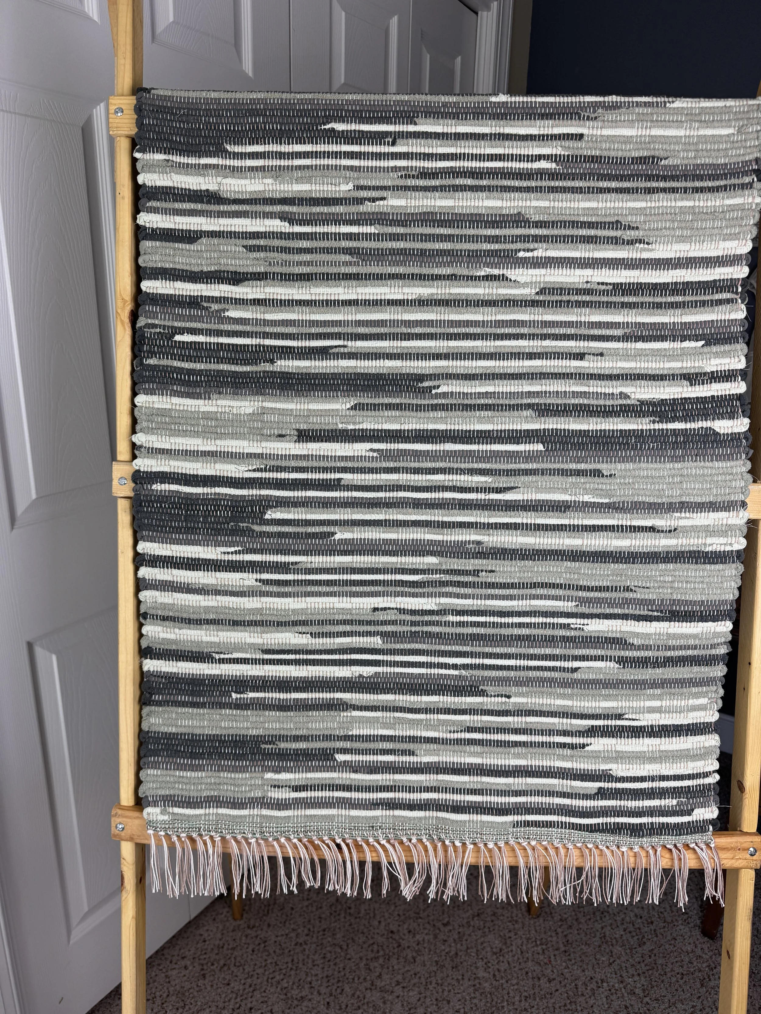 Hanging handmade recycled cotton blends rag rug showing pattern and fringe