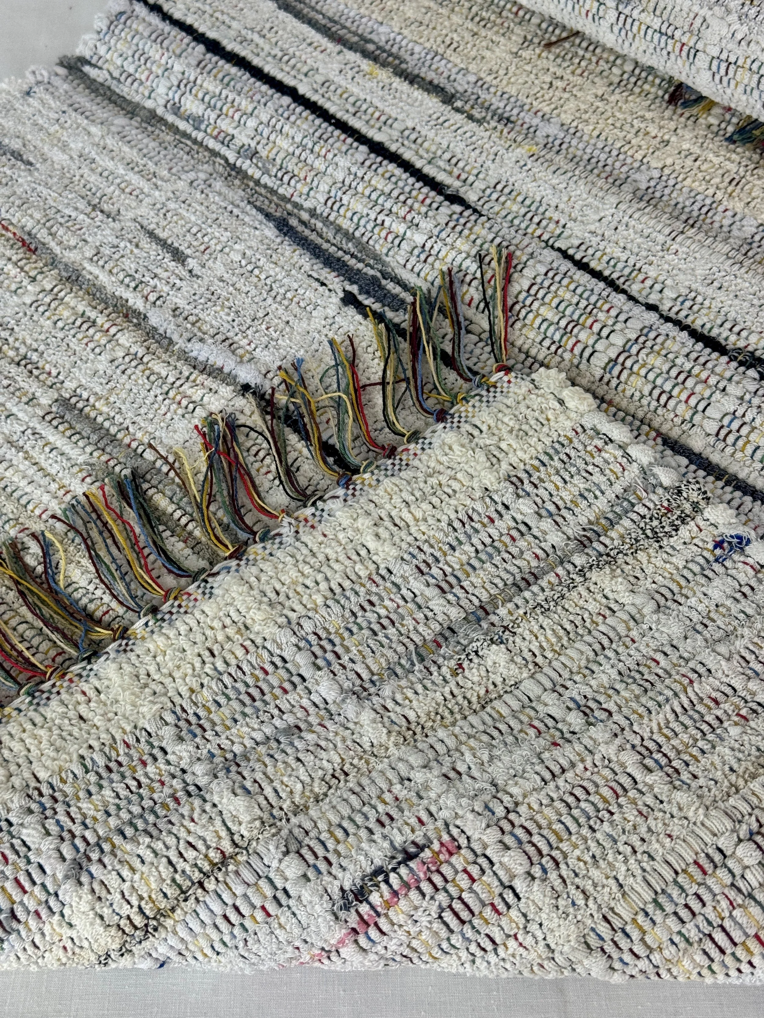 Folded handwoven rag rug showing reverse side and fringe