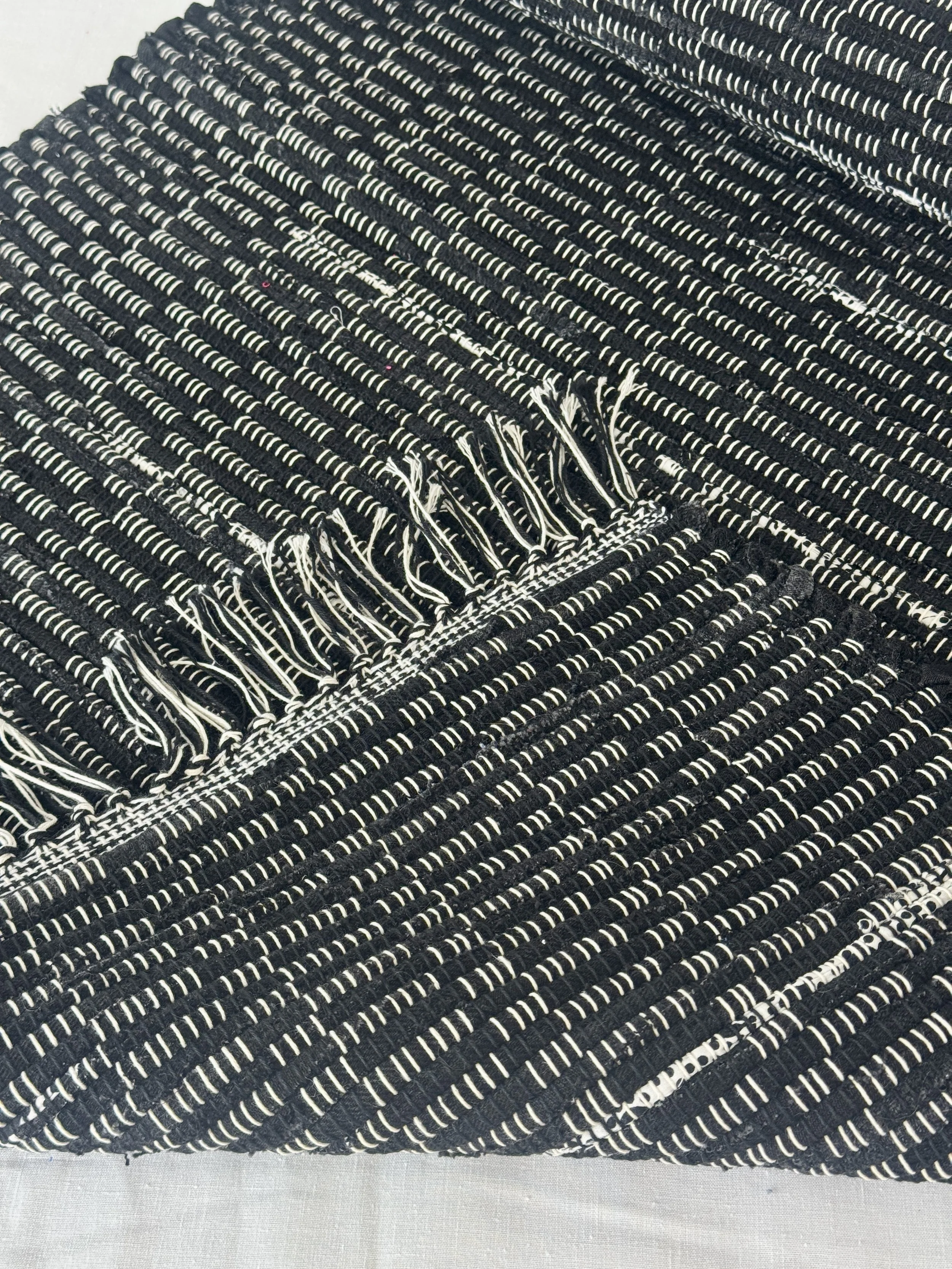 Folded handwoven recycled cotton textiles rag rug showing texture and fringe
