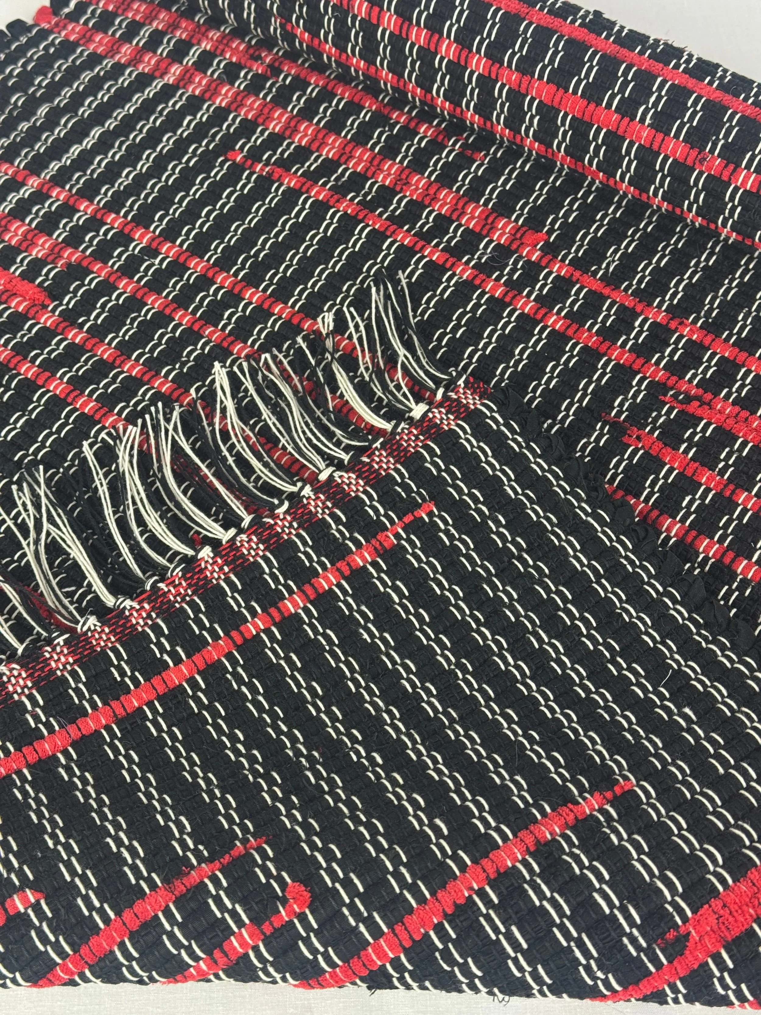 Folded handwoven rag rug showing reverse side and fringe