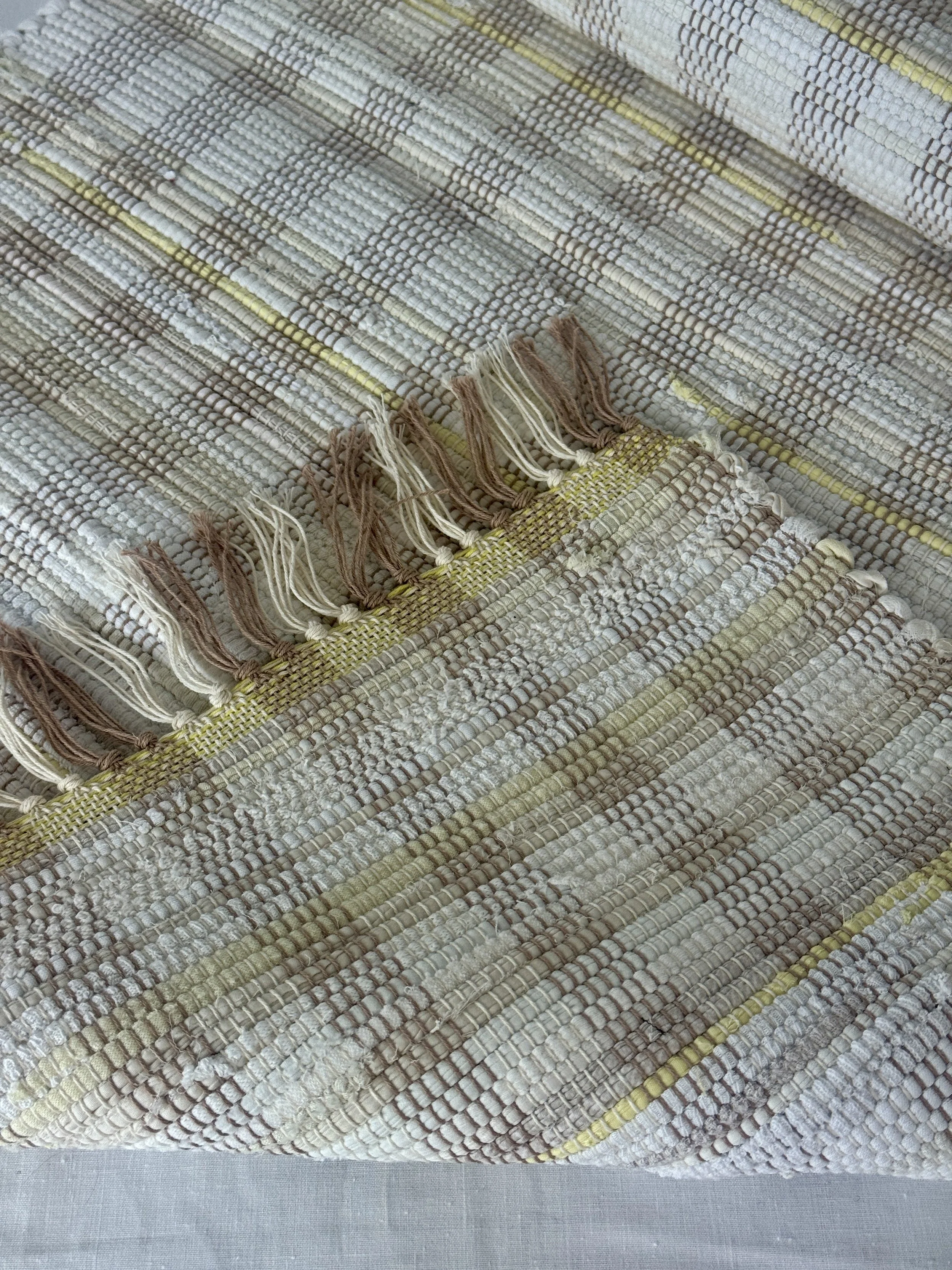 Folded handwoven recycled cotton textiles rag rug showing texture and fringe