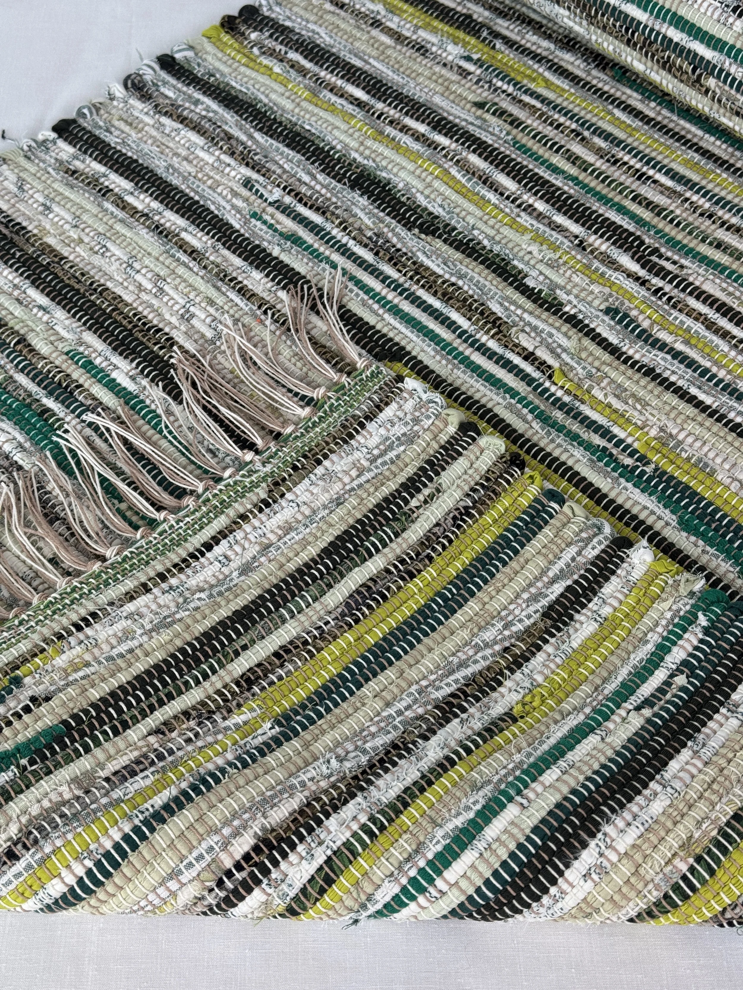 Folded handwoven rag rug showing reverse side and fringe