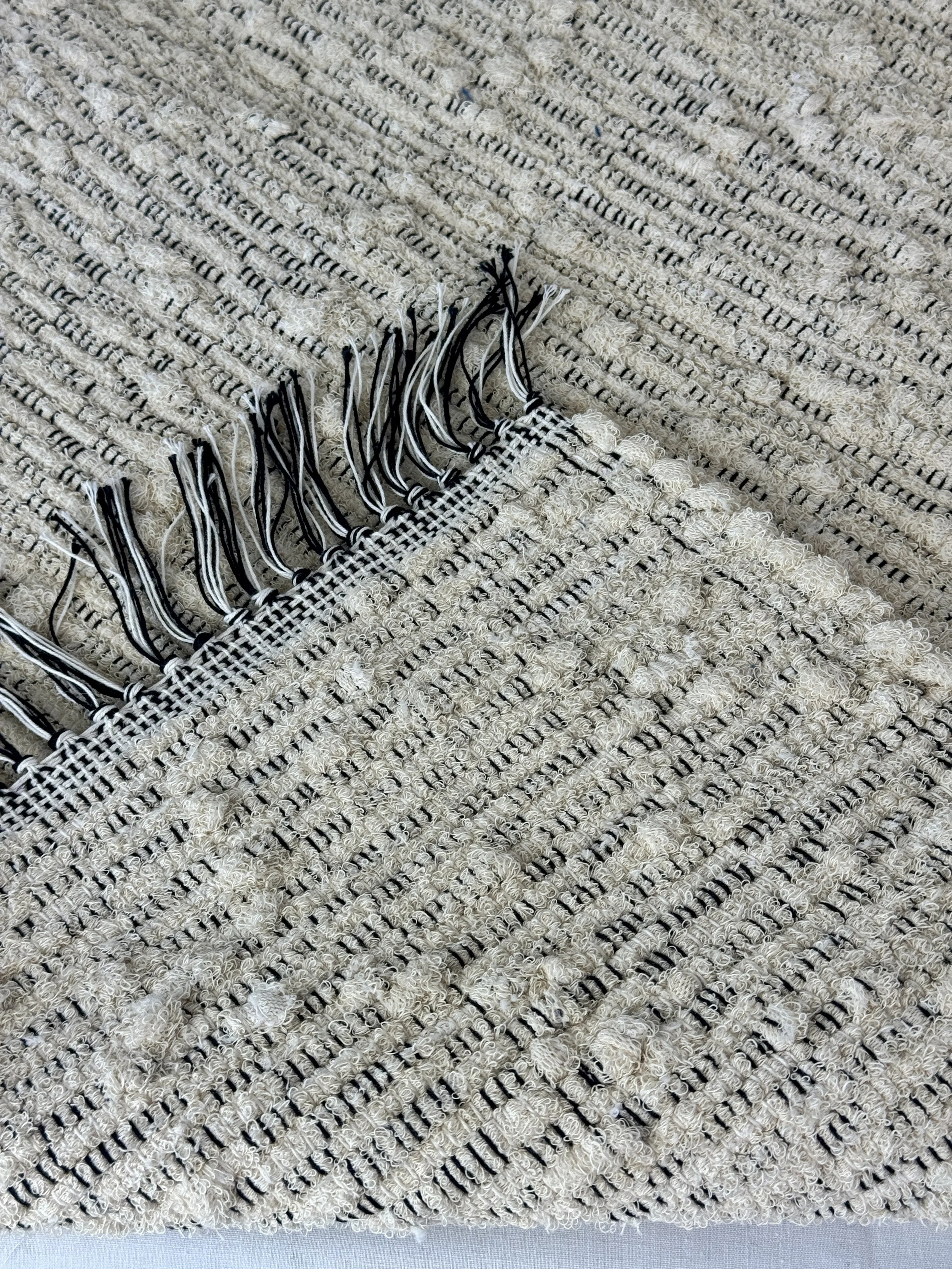 Folded handwoven rag rug showing reverse side and fringe