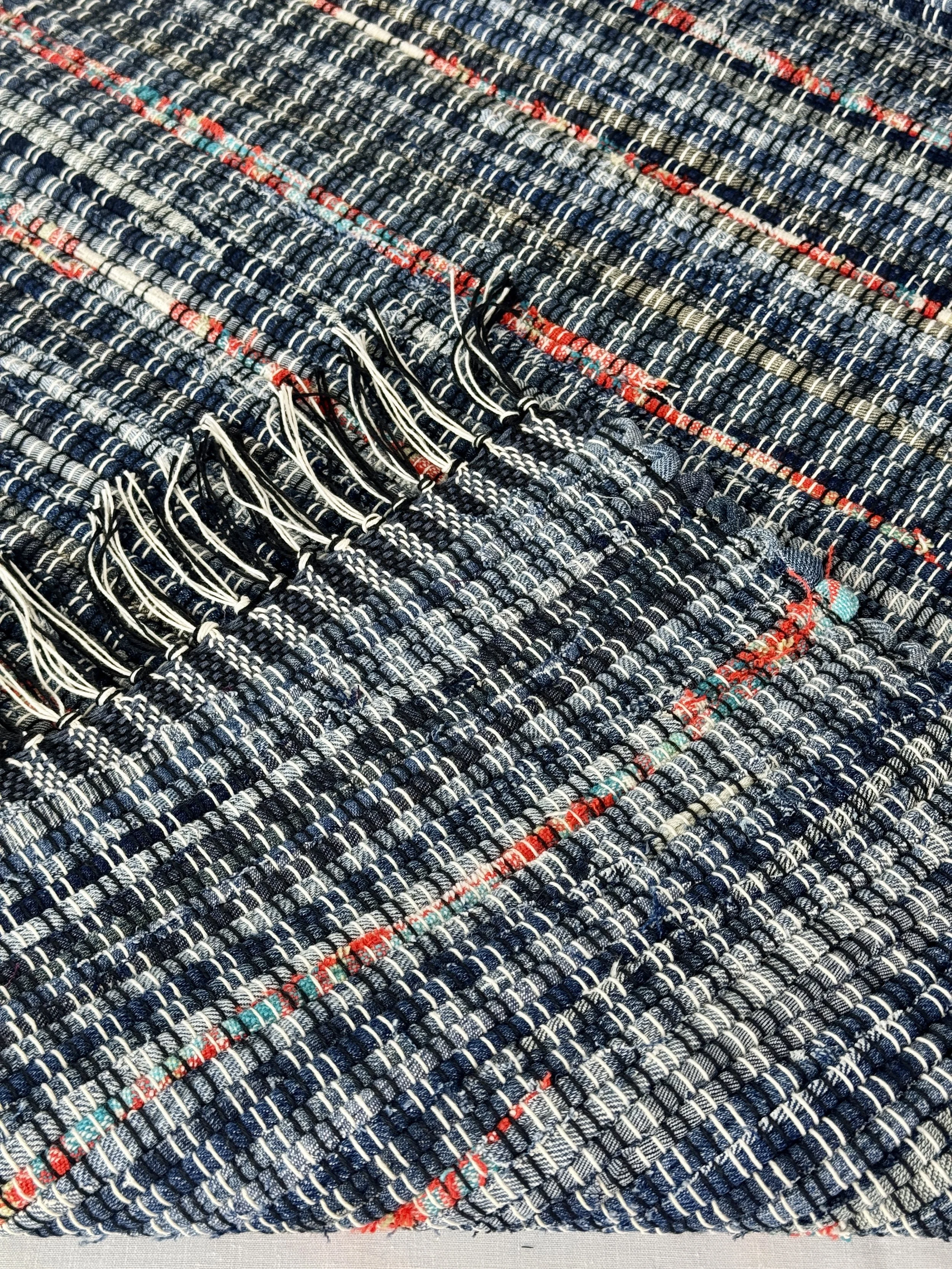 Folded handwoven rag rug showing reverse side and fringe
