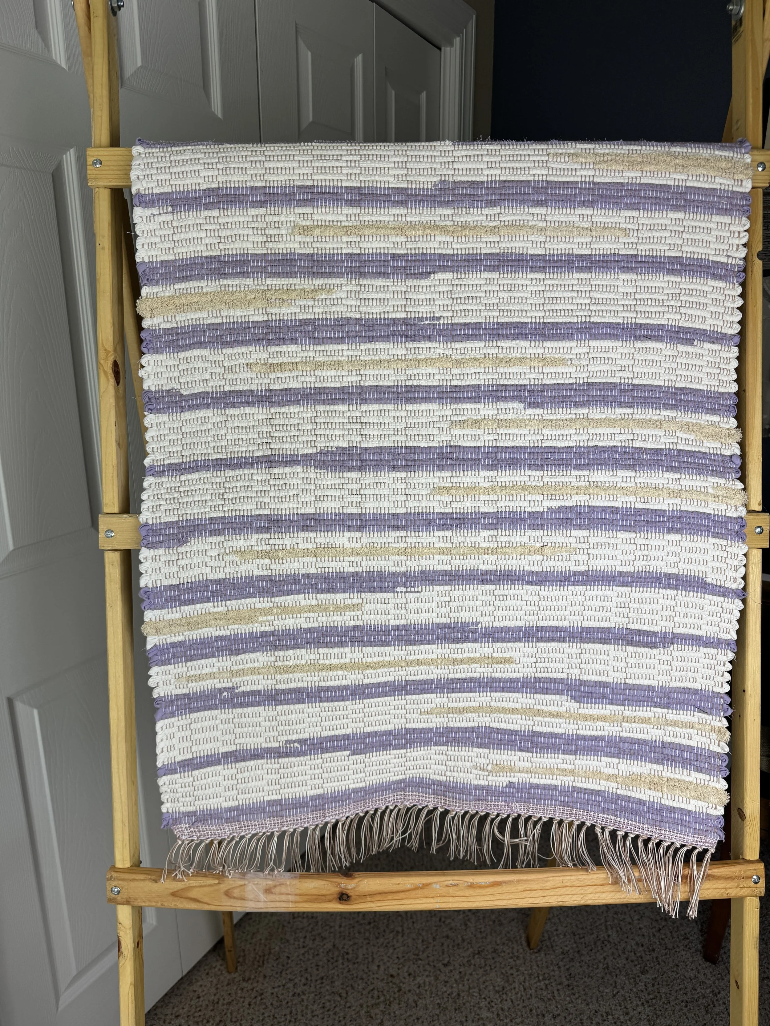 Hanging handmade recycled cotton  rag rug showing pattern and fringe