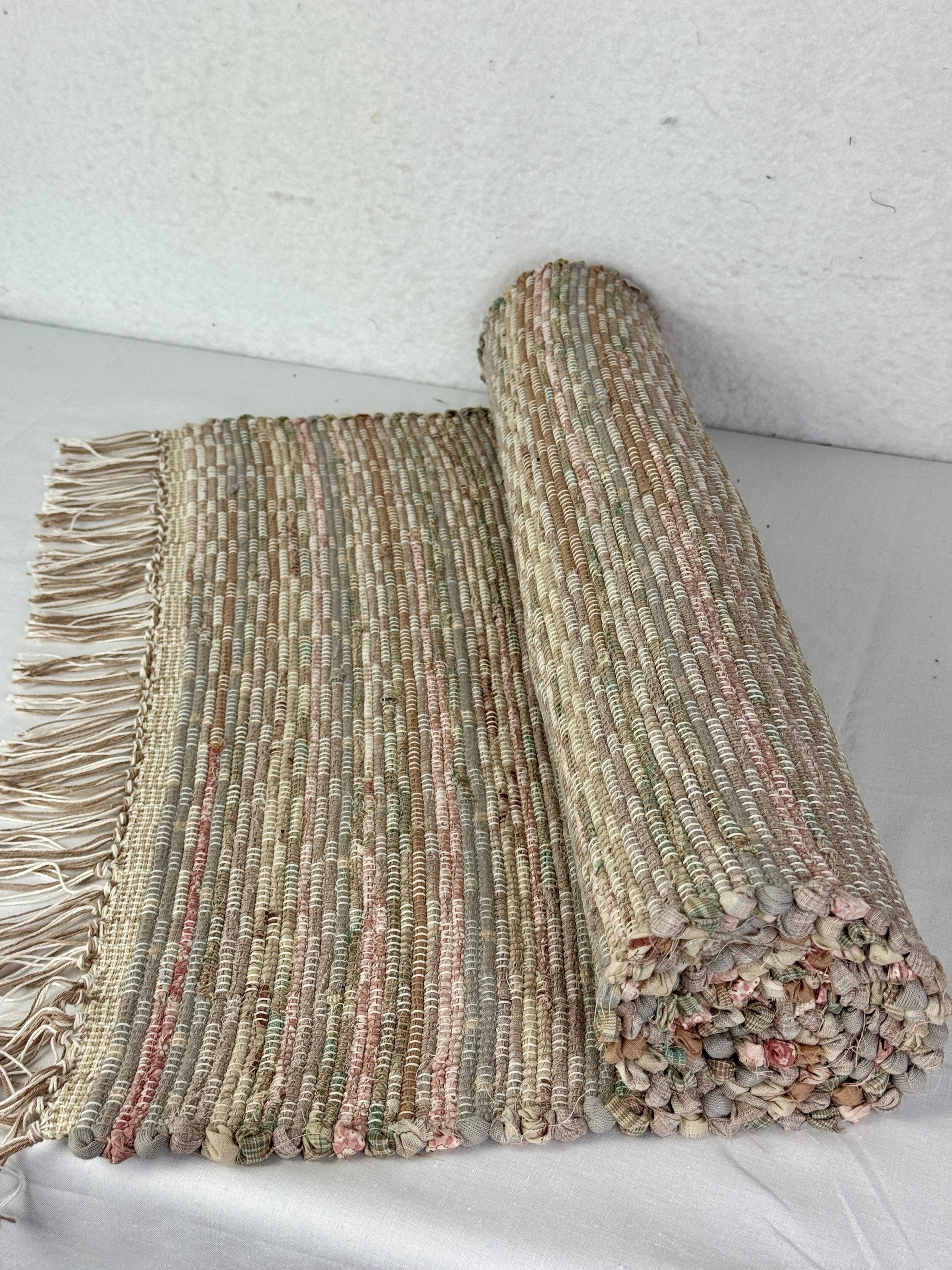 Hanging handmade recycled cotton rag rug showing pattern and fringe