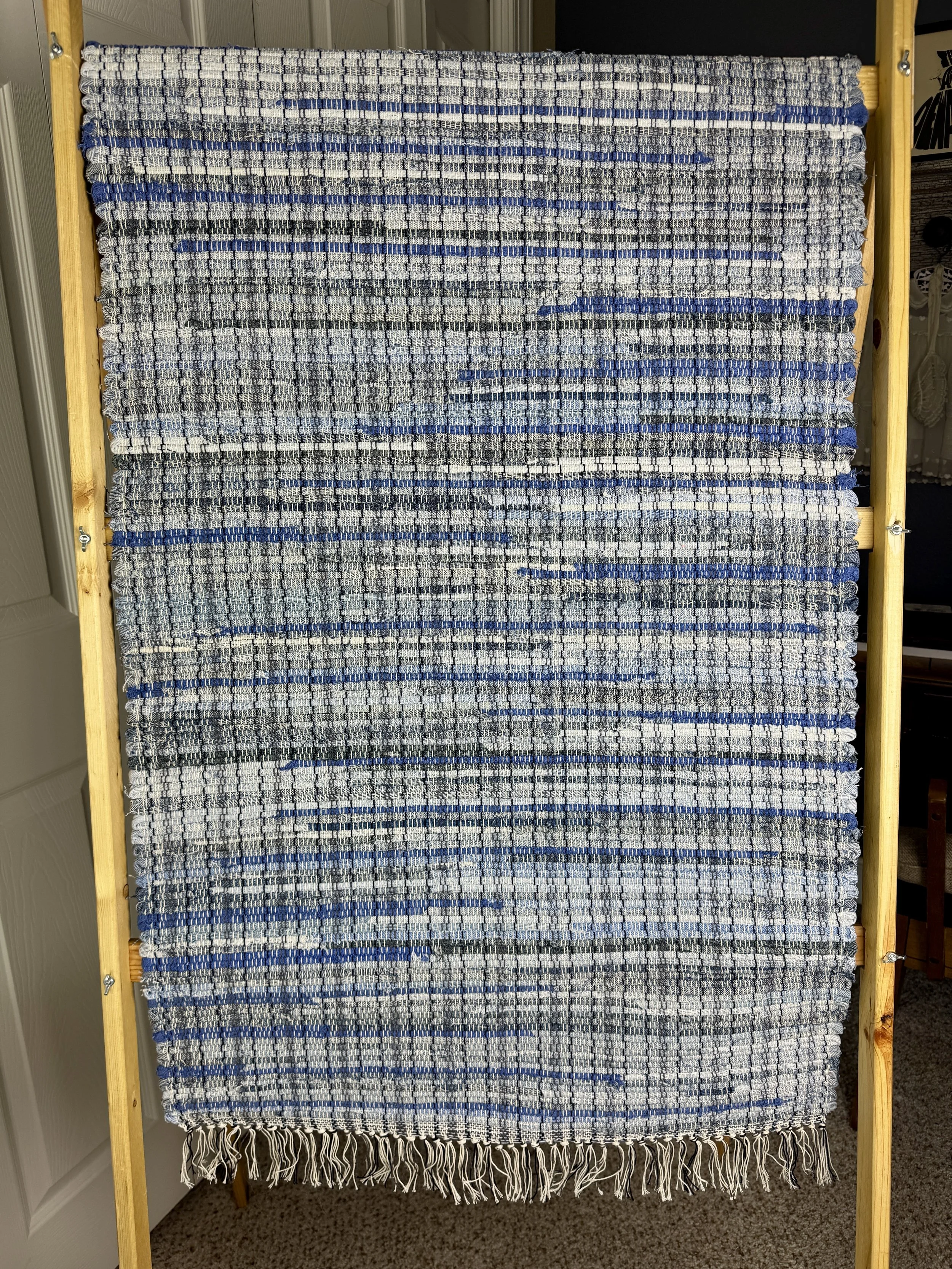 Hanging handmade recycled blue jeans  rag rug showing pattern and fringe