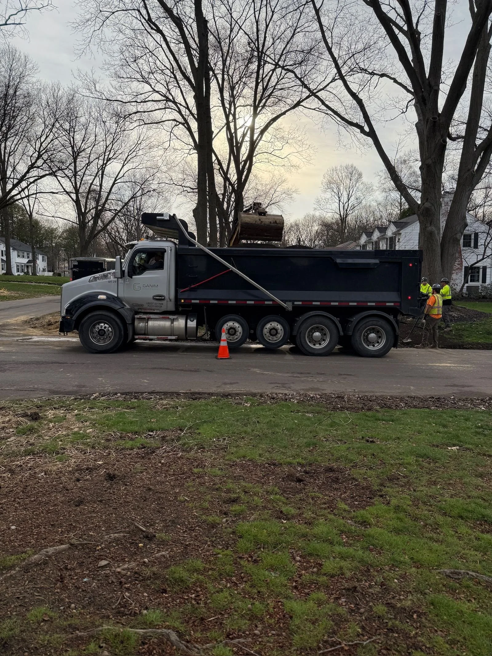Quad axle dump truck positioned on site during residential utility hauling work
