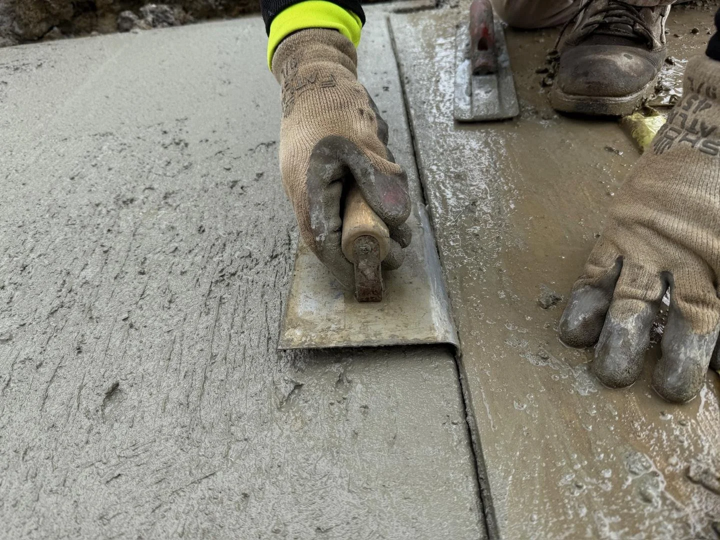 Worker hand-finishes concrete with a trowel for a smooth and durable surface.