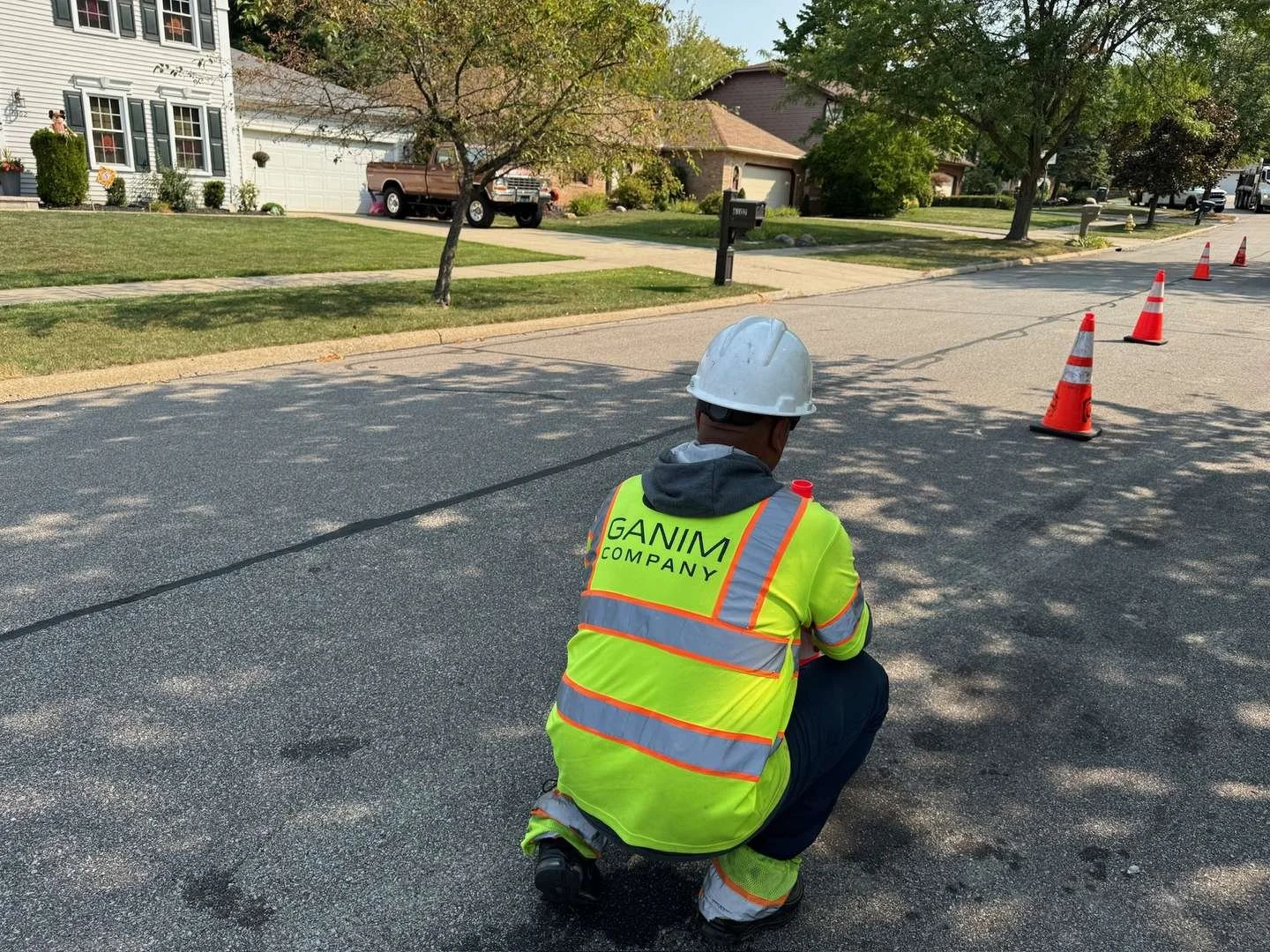 Worker setting up an ATSSA-compliant traffic control zone with cones on a residential street.