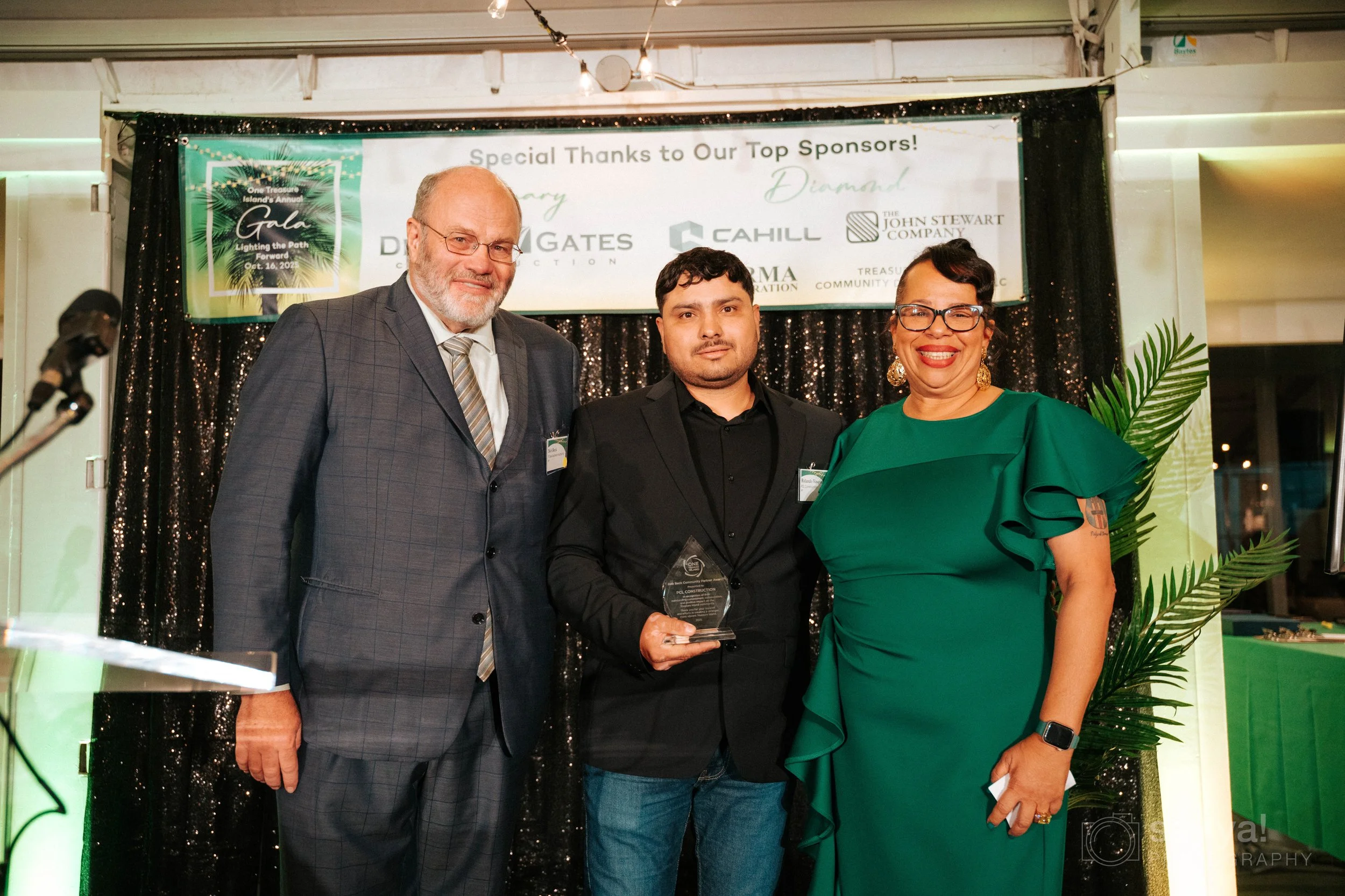 Bob Beck, Director of the Treasure Island Development Authority, and Nella Goncalves, Executive Director of One Treasure Island, presenting PCL Construction with the Bob Beck Community Partner Award