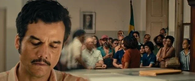 Marcelo facing the left of the frame, with a crowd of people behind him in a government office on the right