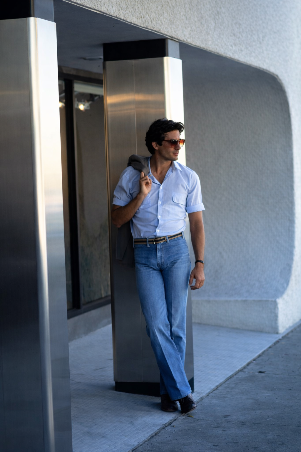 A person in black and white clothing jumping on a rooftop with a city skyline and bridge in the background.