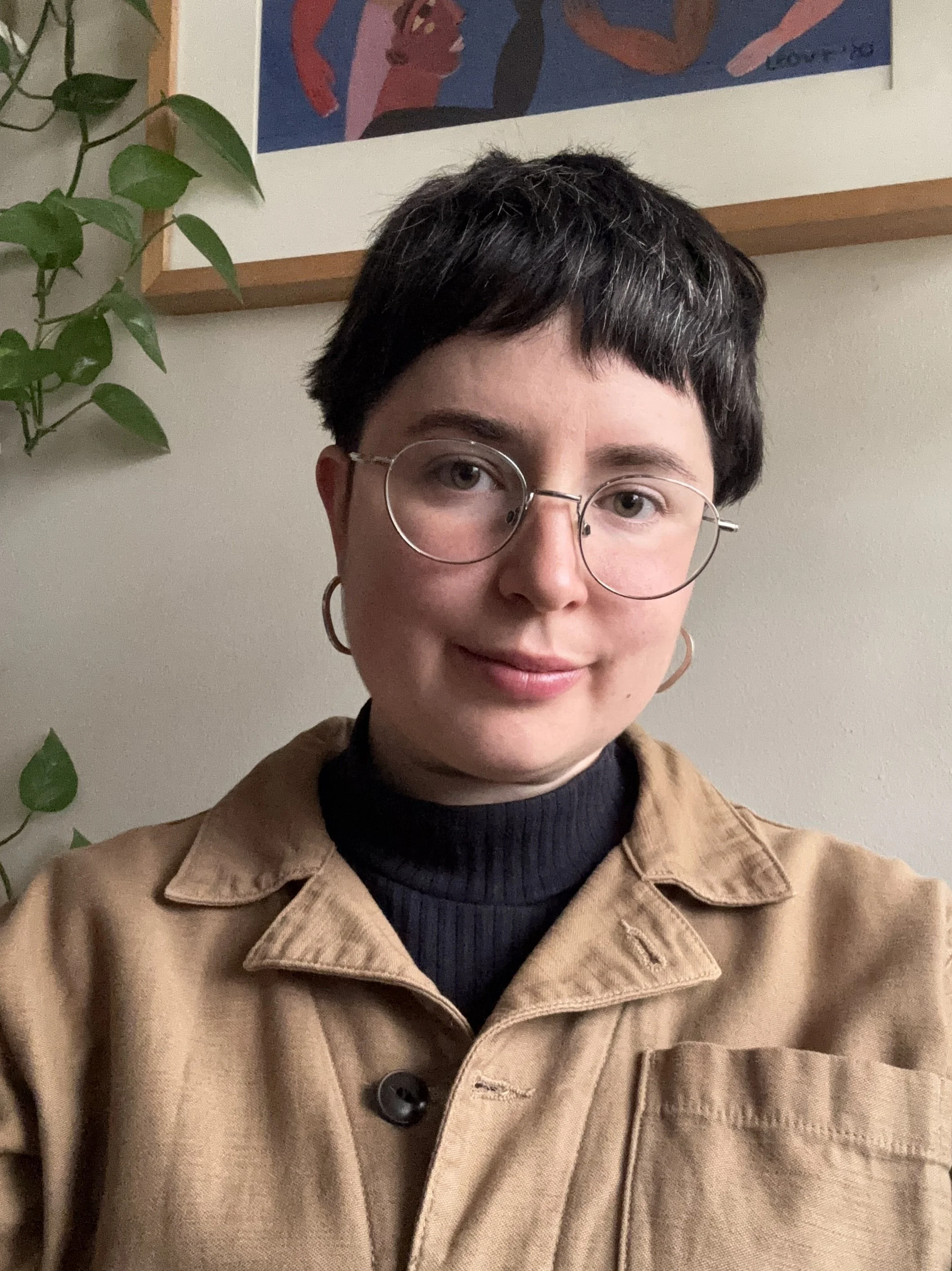 Image of Liz Light in a black turtle neck and a tan jacket. She has short brown hair, glasses, and is softly smiling.