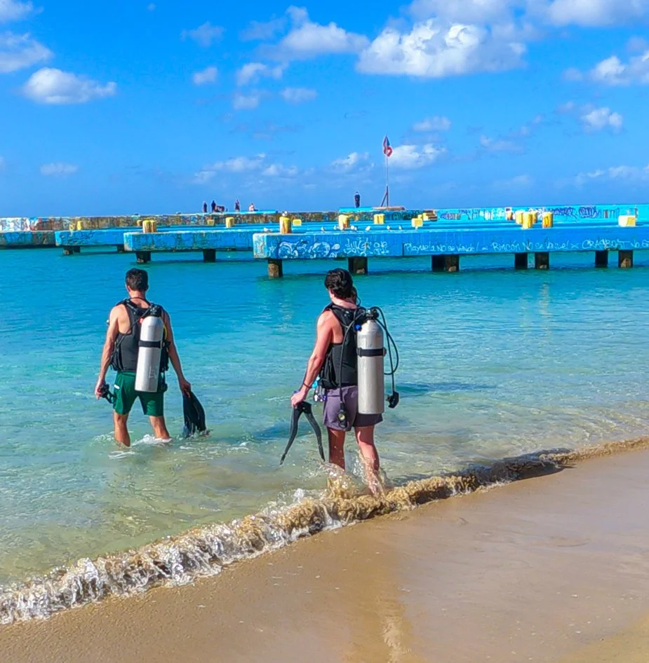 Two scuba divers entering the water for a shore dive in Aguadilla