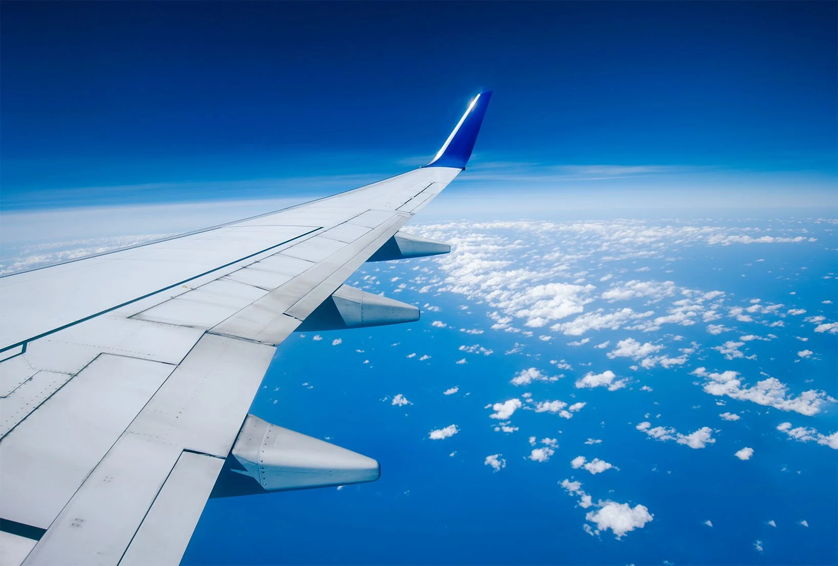 A plane wing soaring across blue skies