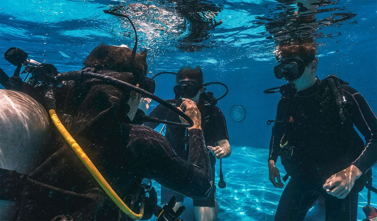 A scuba instructor teaches new students the basics of diving in a pool
