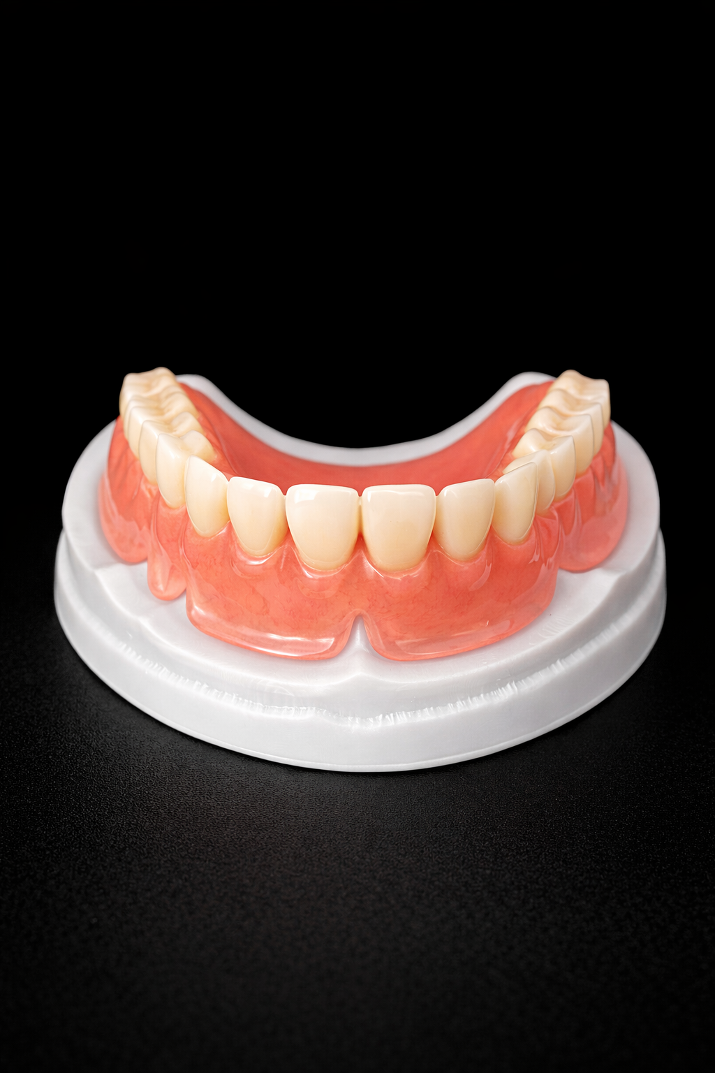 A set of denture teeth displayed on a white base against a black background.