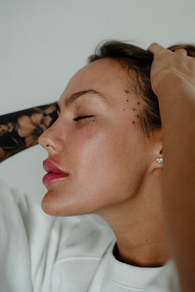 Small star cluster face tattoo beside the eye