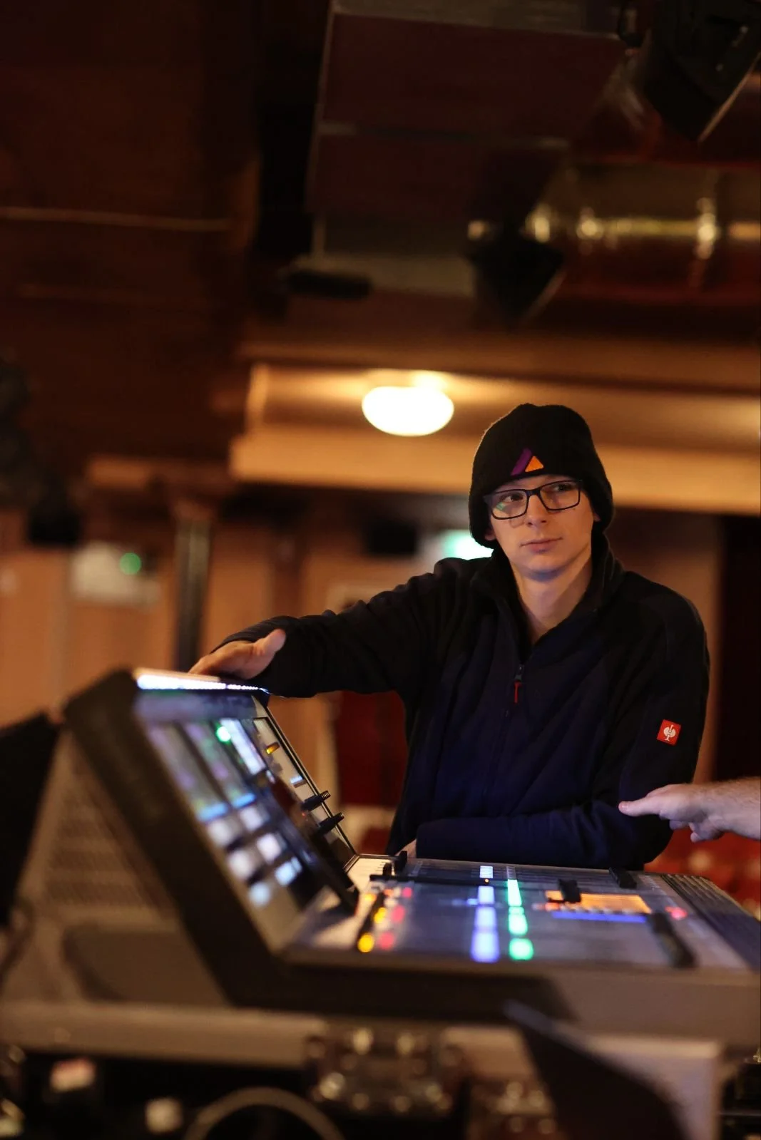 Young person wearing a brown hoodie with orange lining, smiling at the camera.