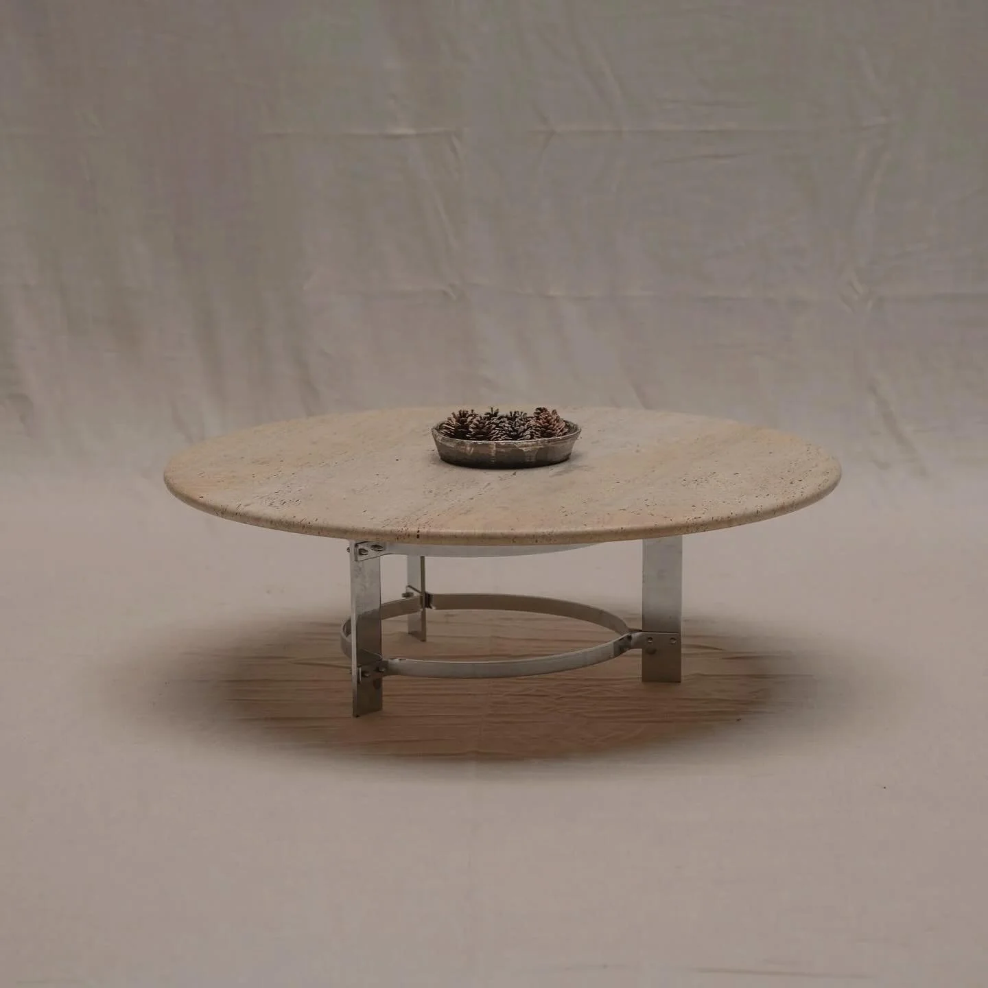 FOR SALE - A modernist coffee table with a bold 120 cm travertine top resting on a refined chromed metal base. The design highlights the contrast between the curved softness of the stone and the clean linear geometry of the structure, creating a stri