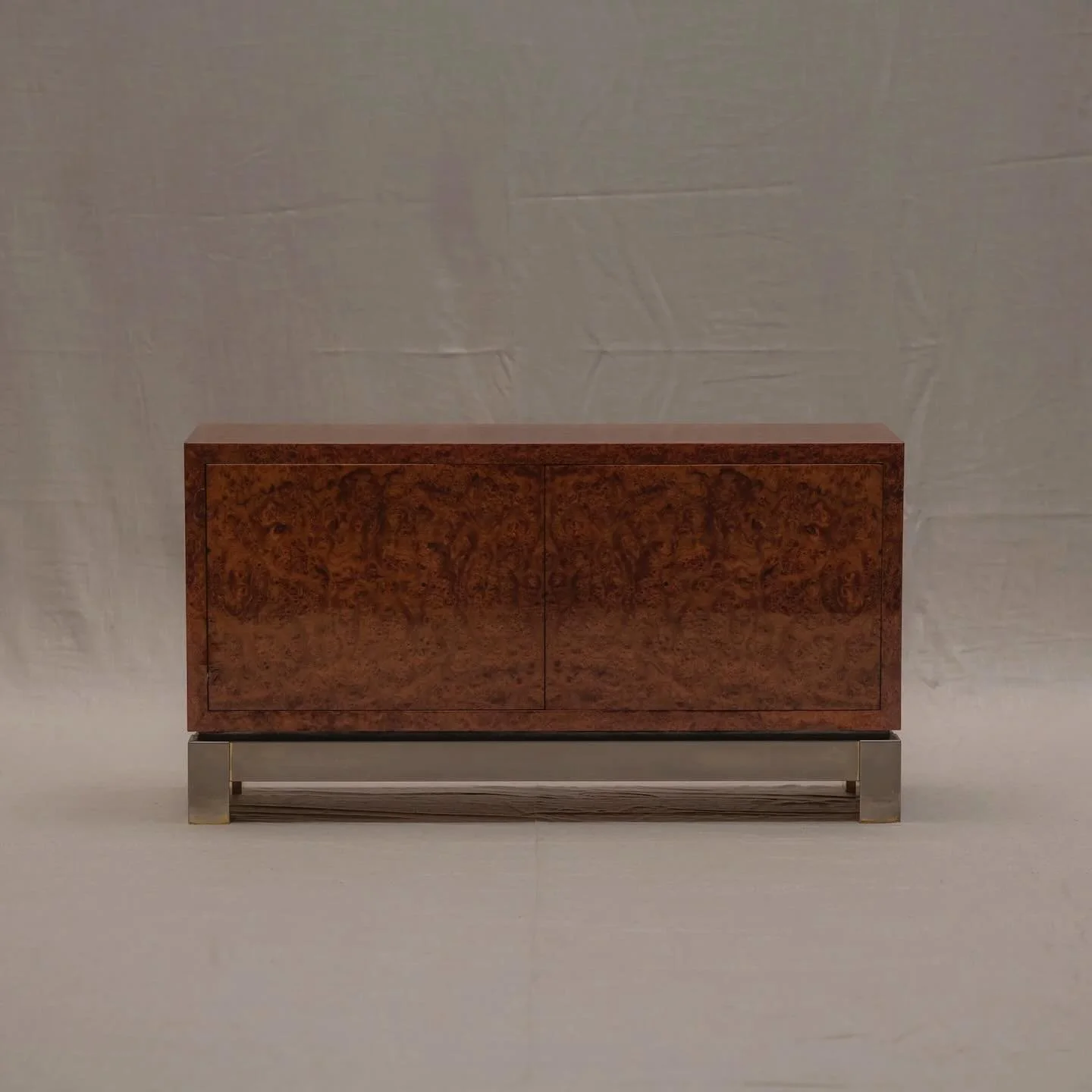 SOLD - An elegant French mid-century cabinet that balances simplicity with material richness. Crafted in the 1970s, it features a striking burl wood veneer, its swirling grain patterns bringing depth and natural drama to the minimalist form. The clea