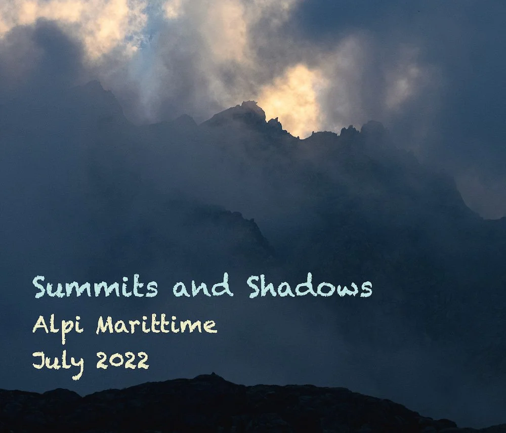 Mountain range with clouds and sunlight in the background, overlaid with text that reads "Summits and Shadows, Alpi Maritime, July 2022."
