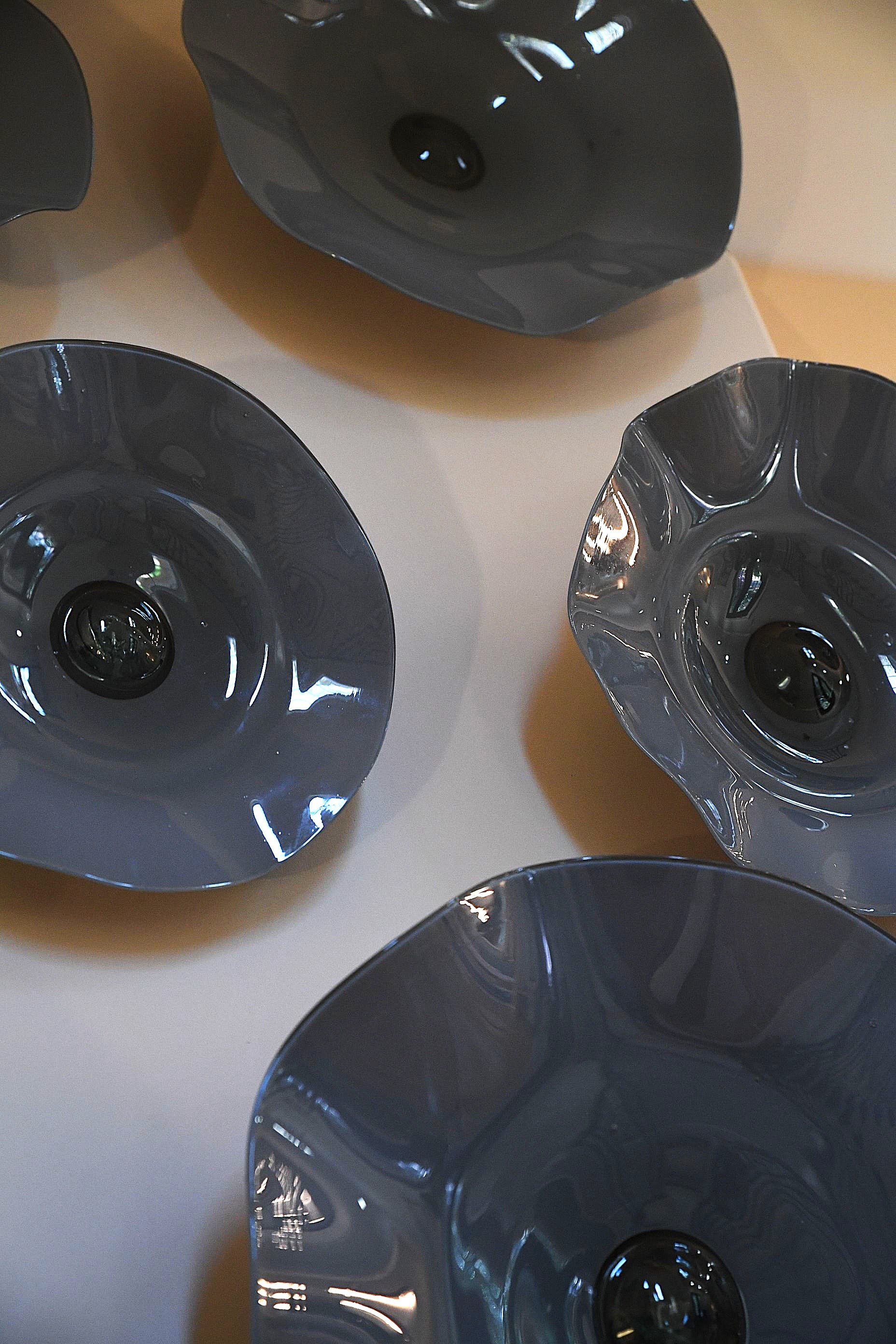 Close-up of sculptural glass wall art featuring organic shapes, glossy finishes, and dimensional texture
