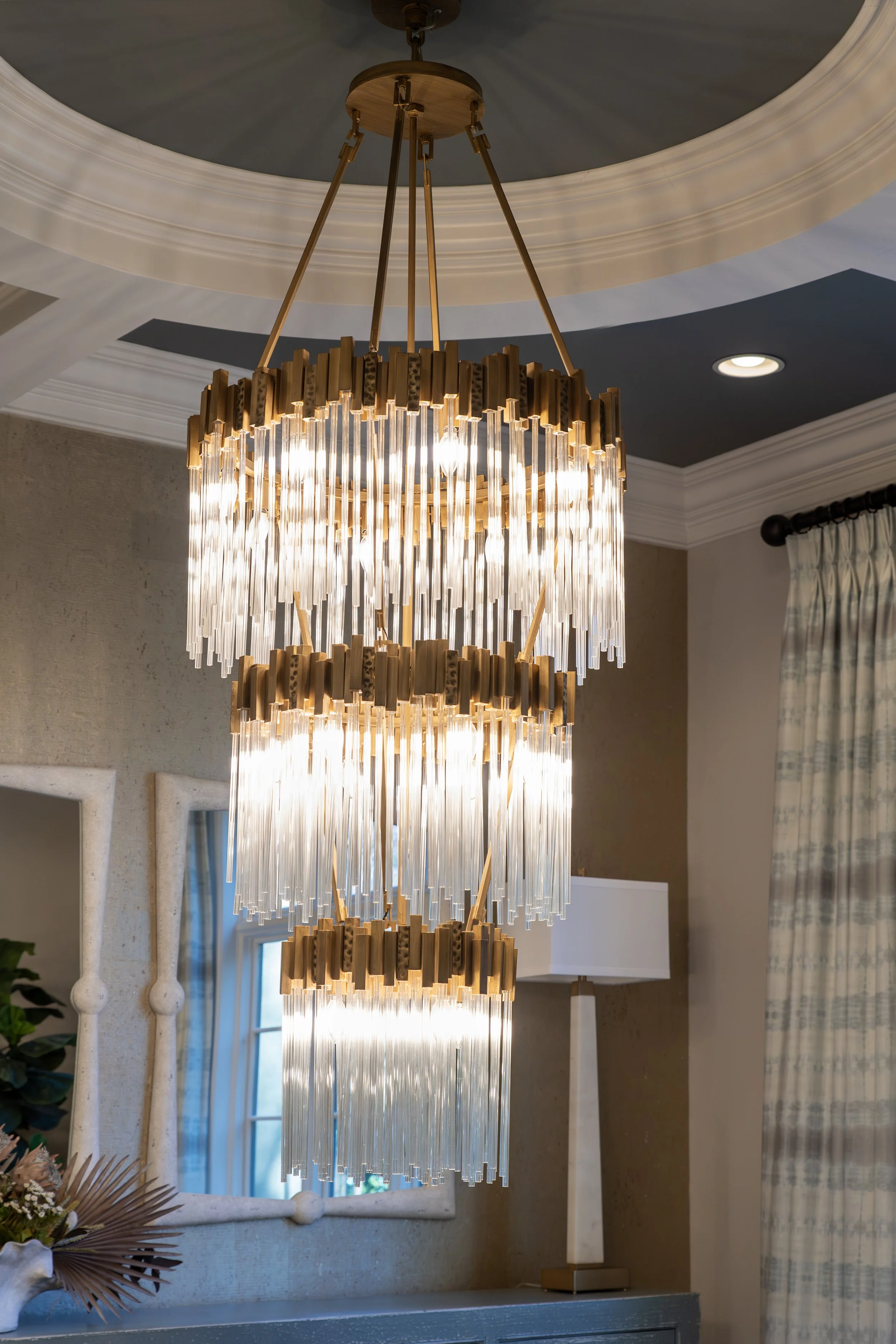 Elegant three-tier crystal chandelier with warm brass accents illuminating a sophisticated dining space