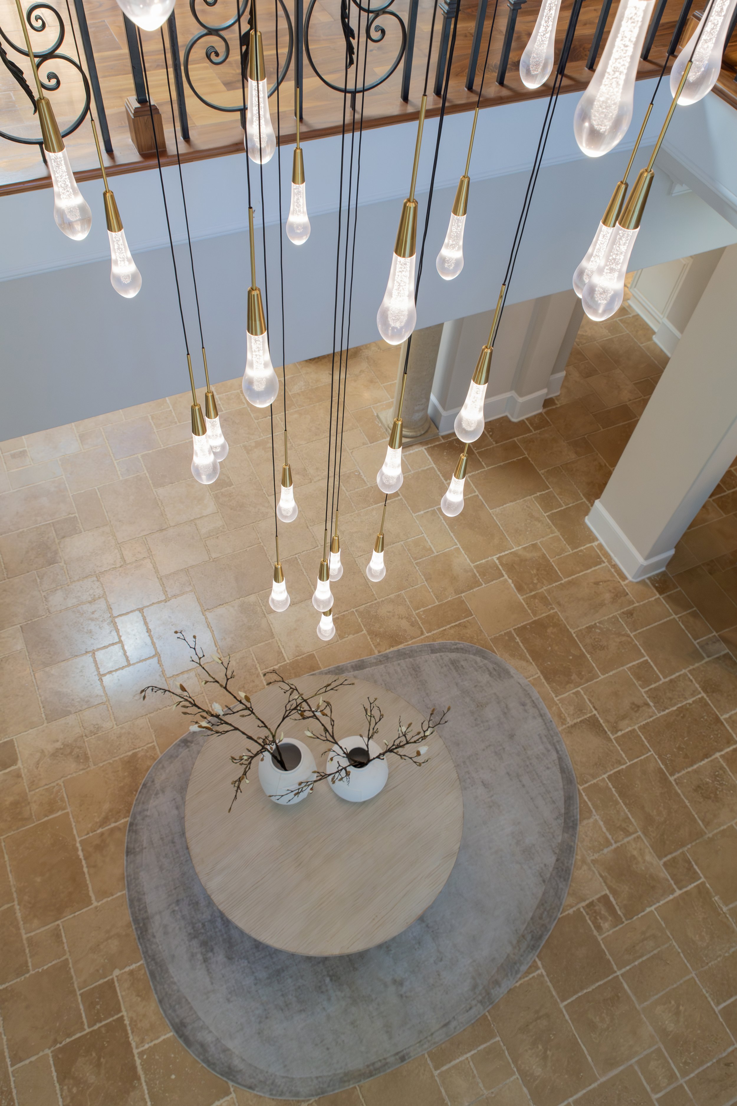 Close-up of sculptural glass raindrop pendant lights glowing with warm ambient lighting in a luxury foyer