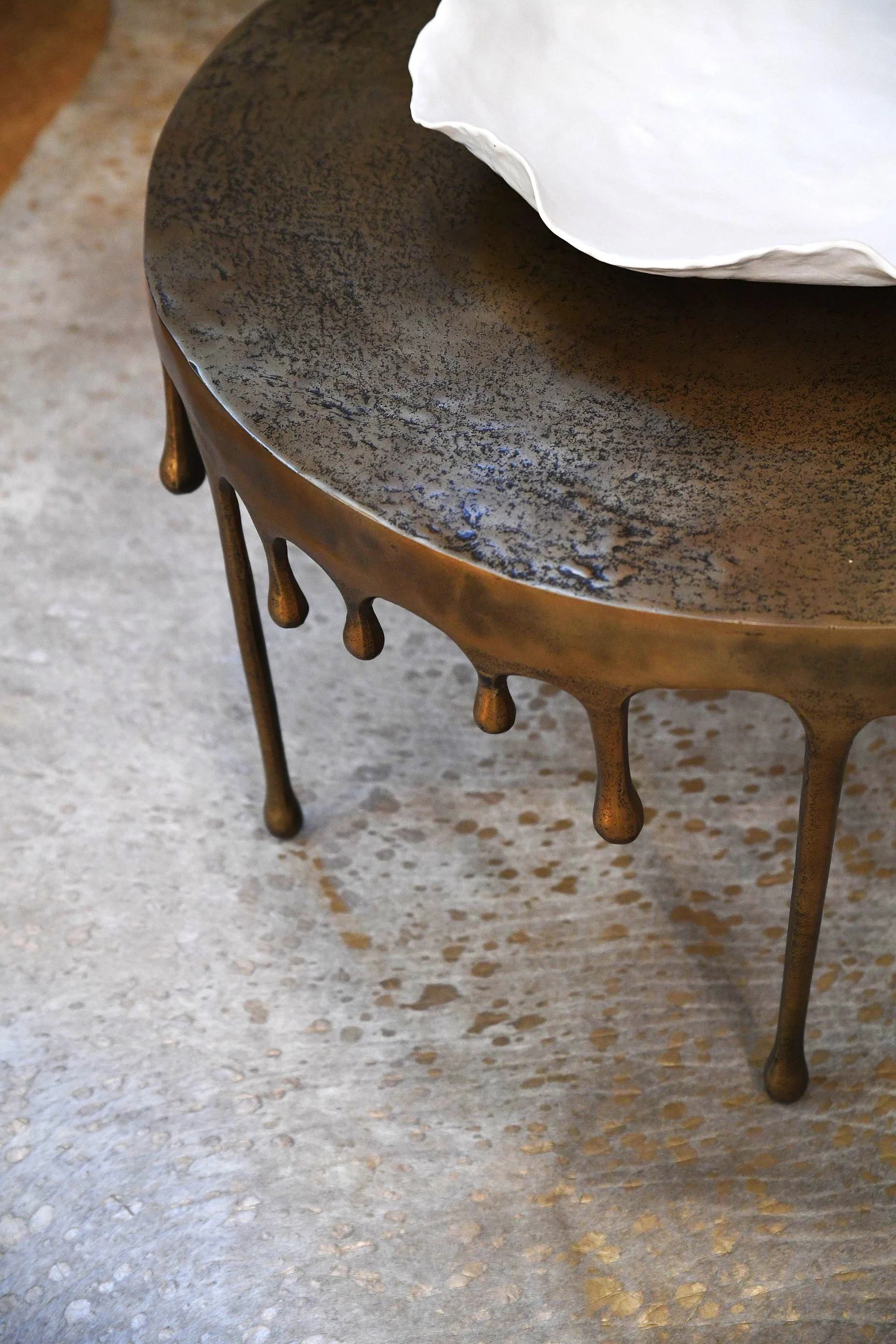 Artistic bronze accent table featuring a dripping metal edge detail and organic sculptural styling