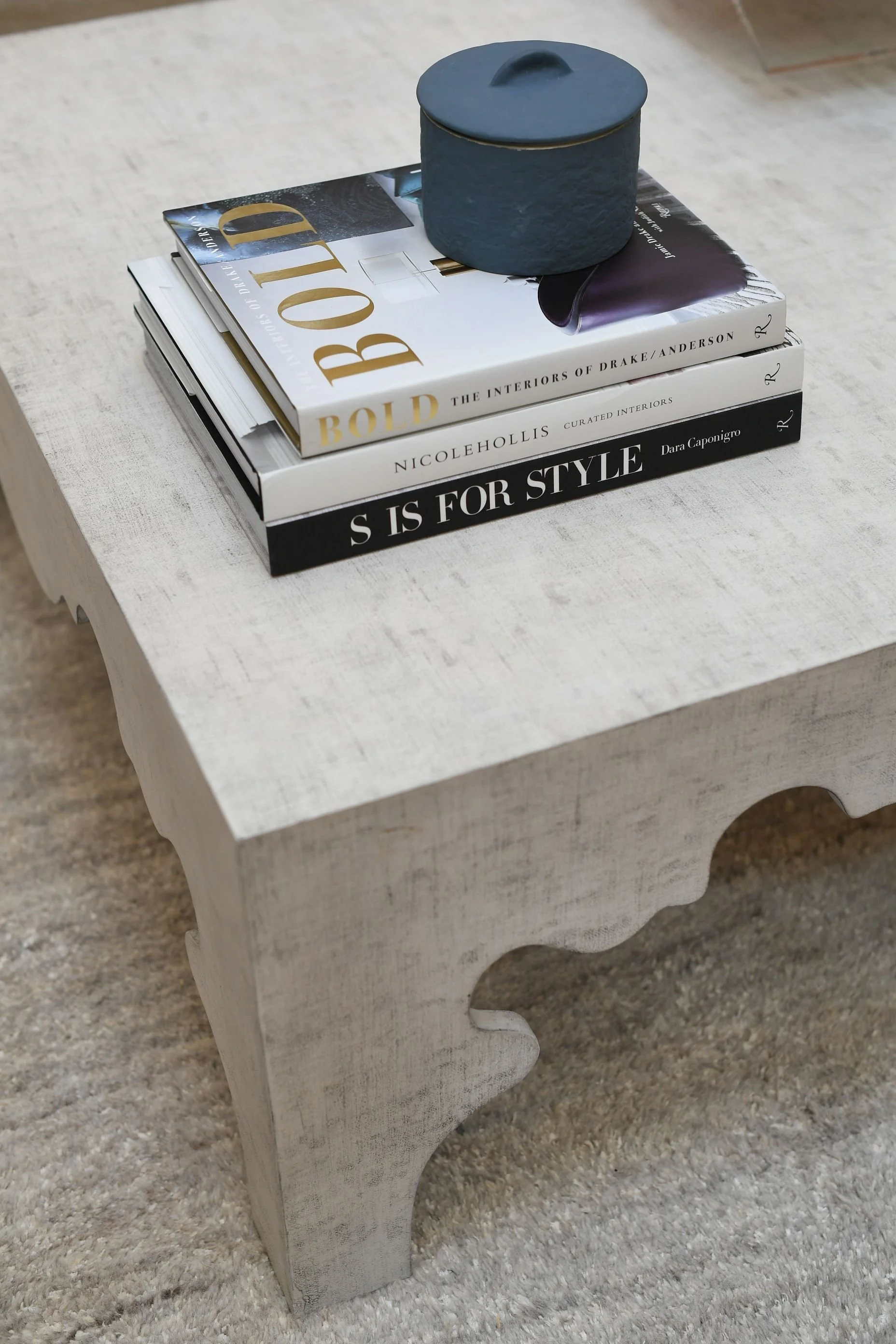 Styled coffee table featuring luxury design books, decorative accessories, and layered neutral textures