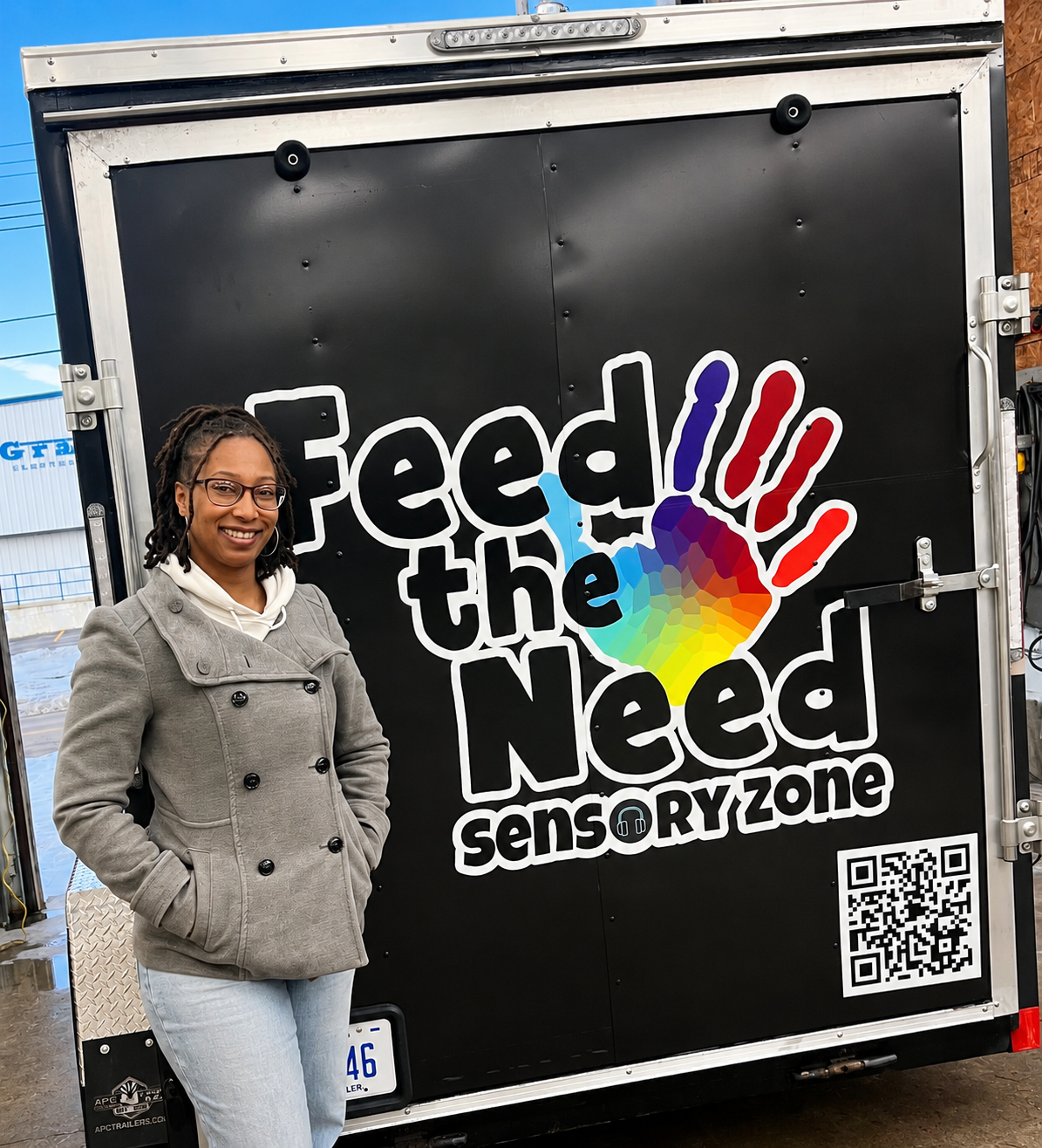 Tiana Haywood, founder of Feed the Need Sensory Zone, standing beside the organization's sensory trailer in Michigan.