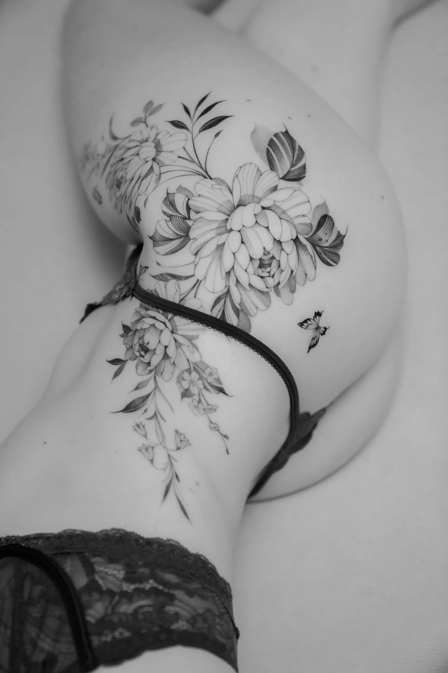 Tatuaje floral fine line en la cadera, en blanco y negro