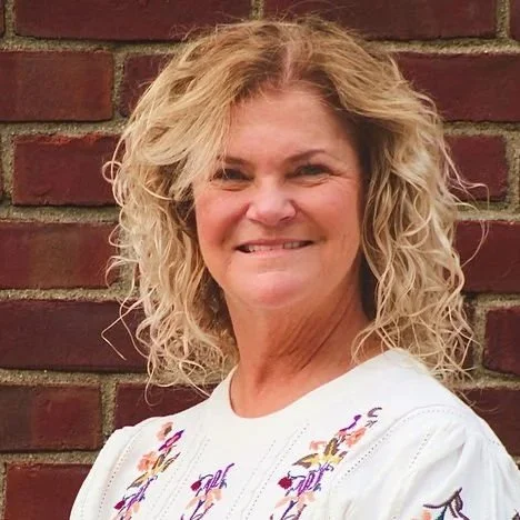 Sally against a white background in a flowered top