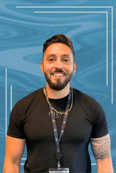 A smiling man with dark hair and a beard, wearing a black t-shirt and a lanyard, standing in front of a blue abstract background.
