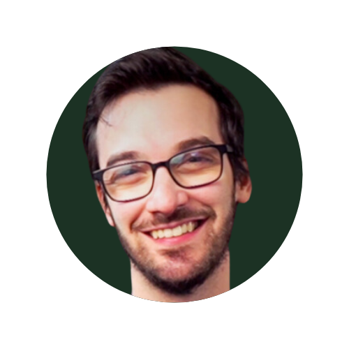 Zach Heyde, Portrait of a smiling person wearing glasses against a dark background.