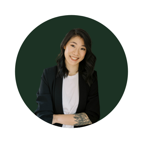 Alicia Koo, owner of Daily Atelier, Smiling person with long dark hair, wearing a black blazer and white shirt, green background.