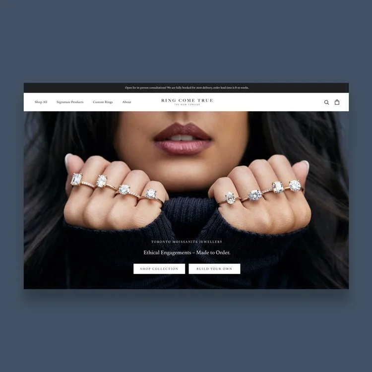 Close-up of a woman's face and hands showcasing multiple diamond rings on her fingers, with a dark sweater and a blurred background.