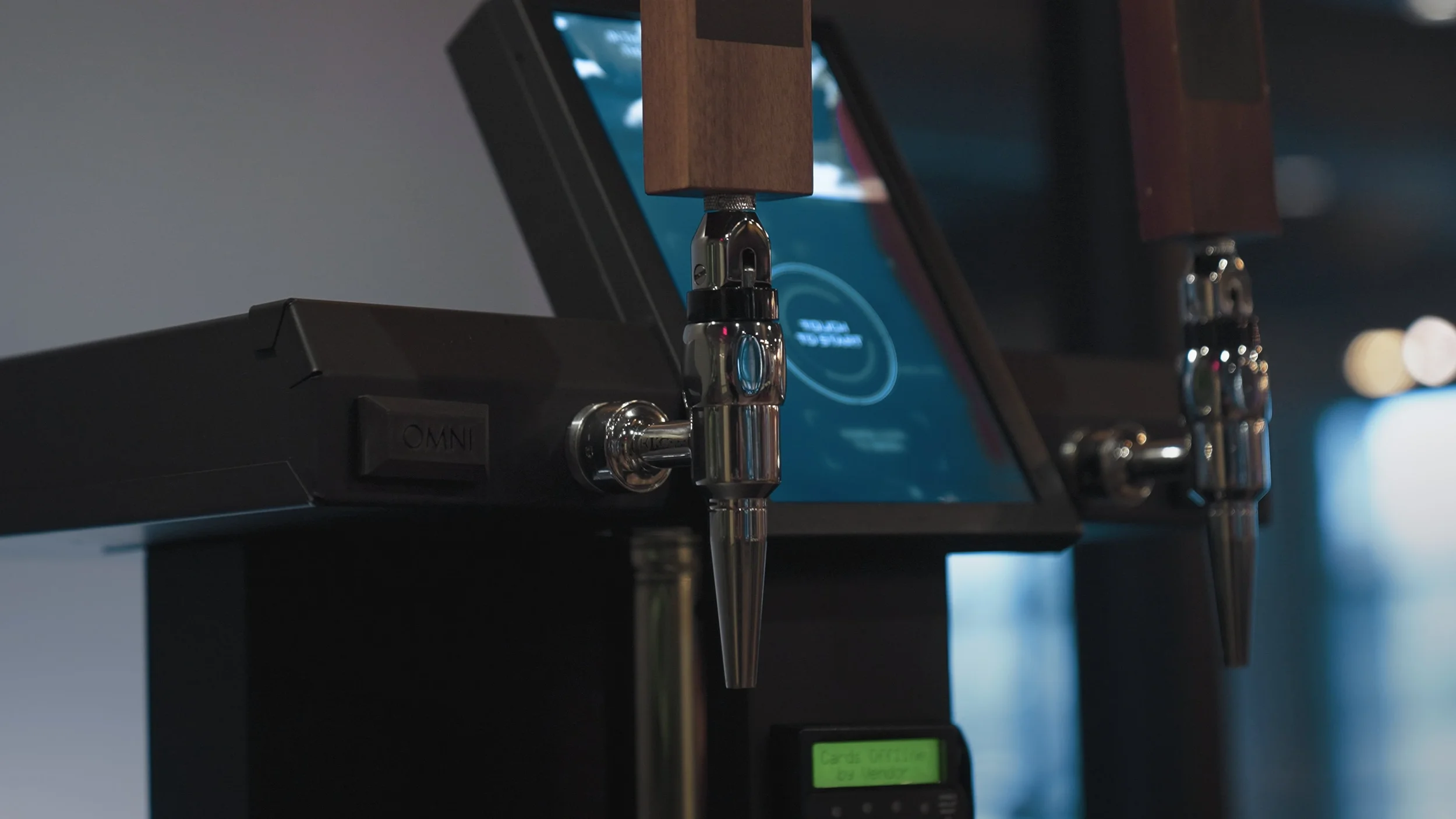 Close-up of a coffee brewing machine with metal spouts and a digital control screen.