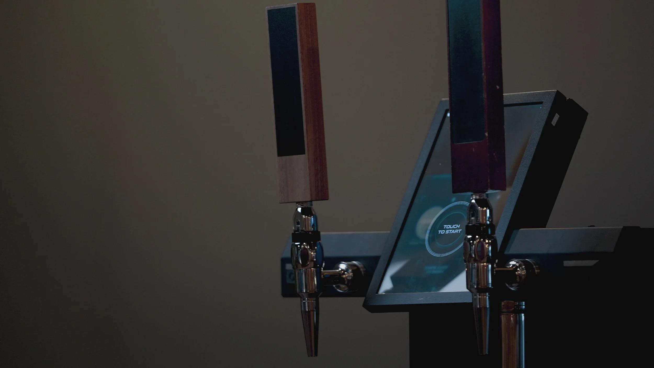 A robotic machine with two robotic arms holding wooden paddles, with a digital touchscreen display stating 'Touch to Start'.