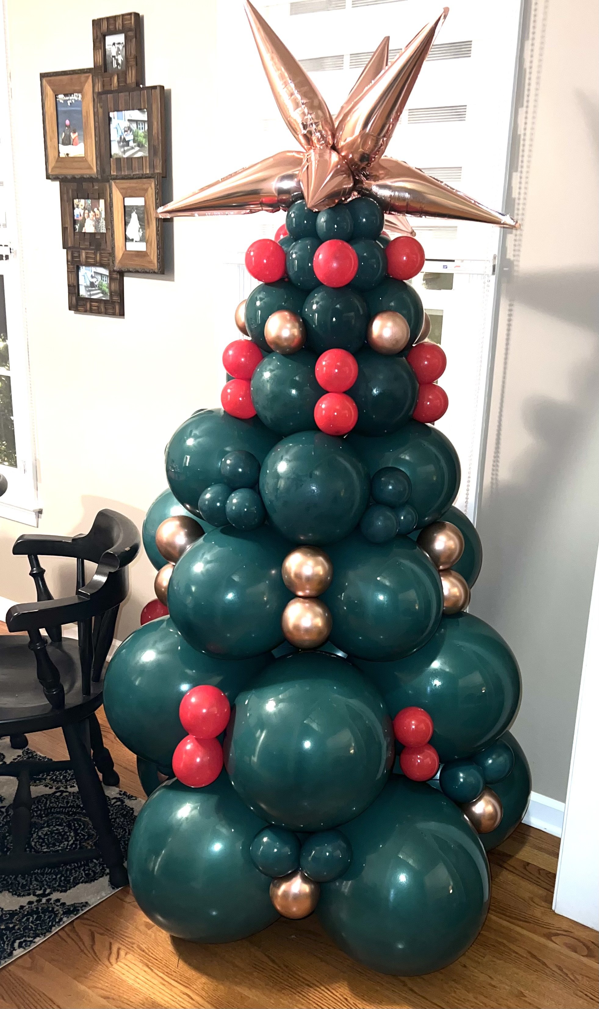 Balloon Christmas tree made of green, red, gold, and bronze balloons topped with a large gold star balloon.
