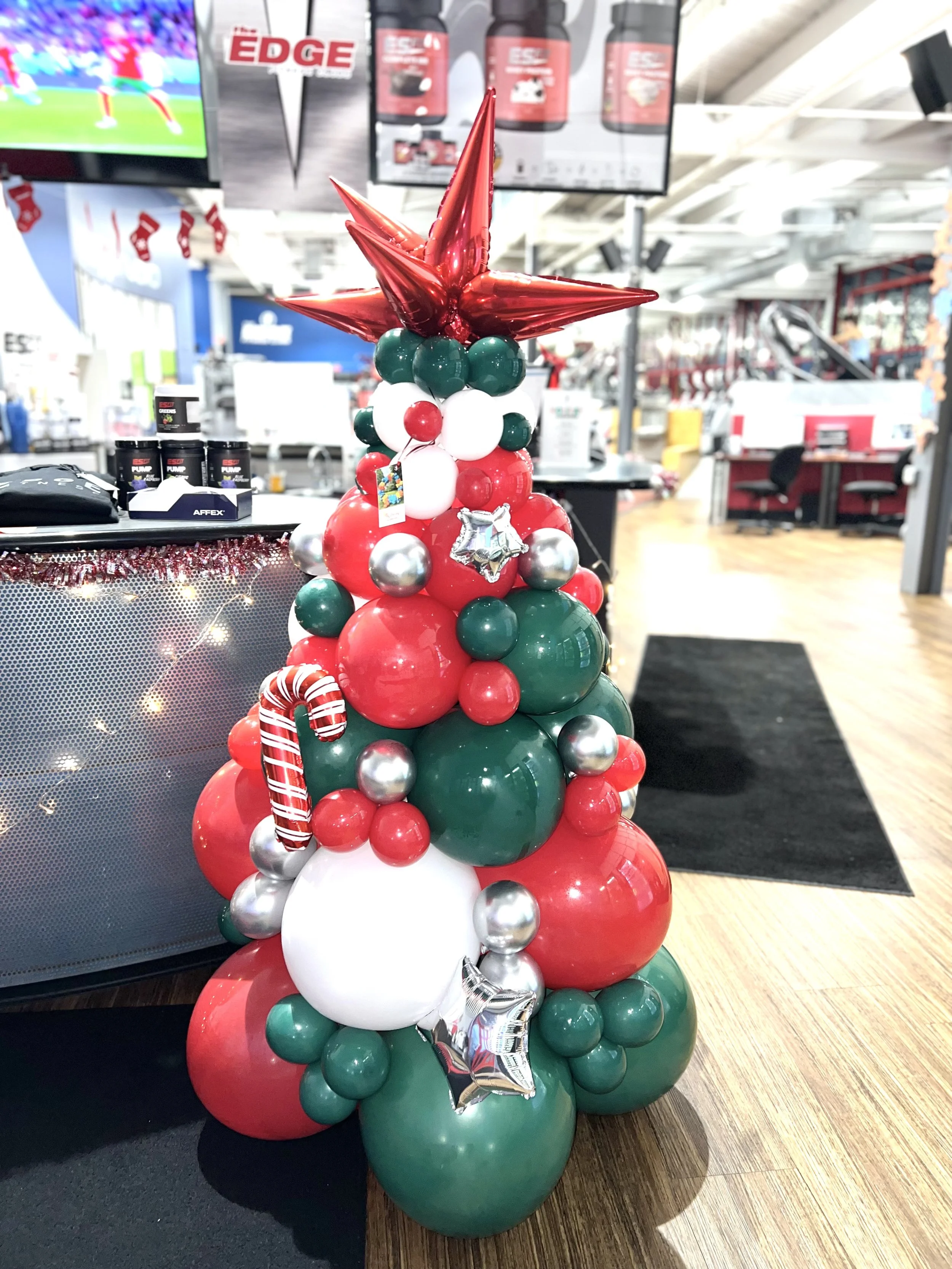 Christmas balloon tree decorated with red, green, white, and silver balloons topped with a red star-shaped balloon.