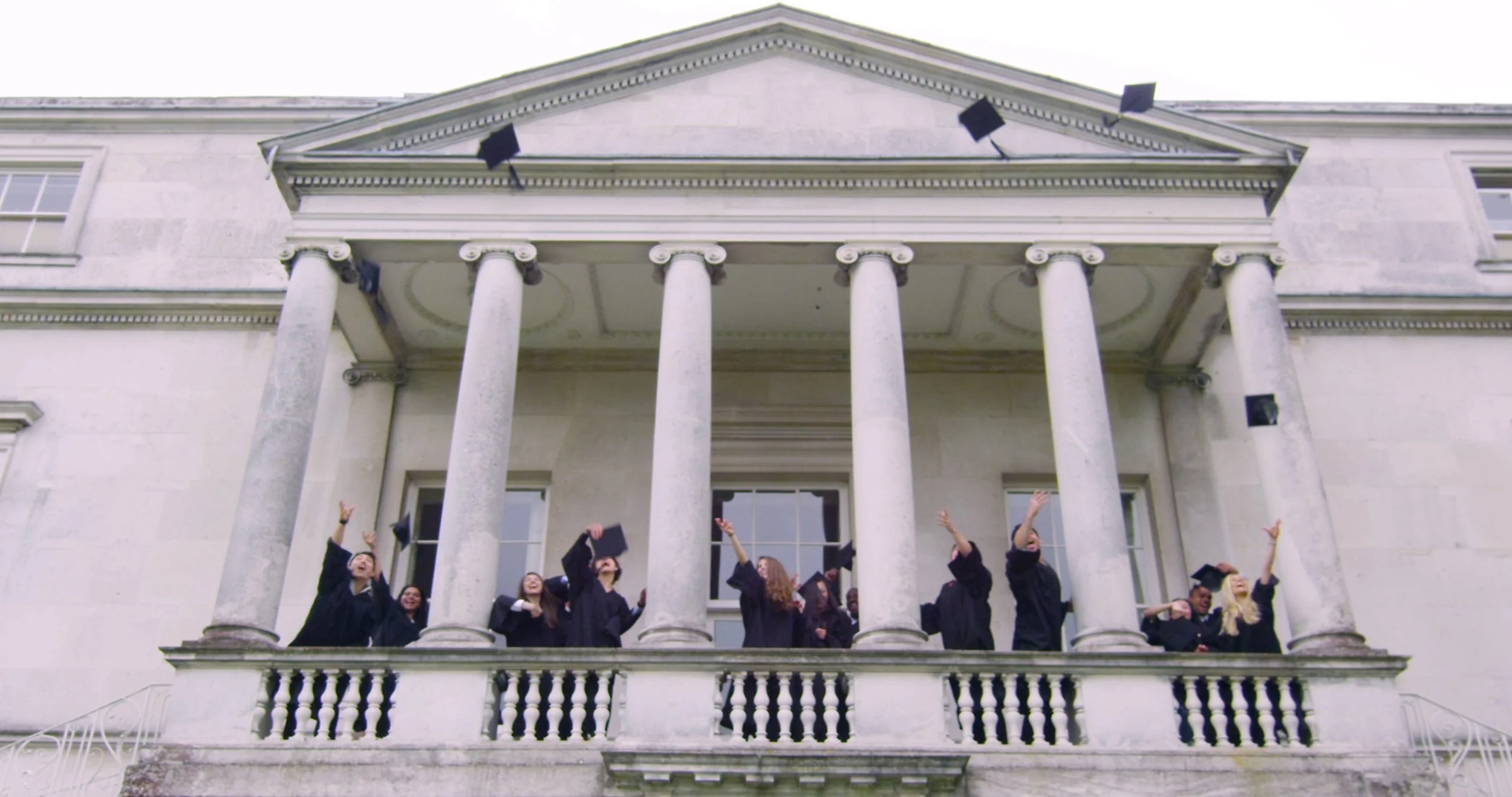 Students gathered on the steps of a columned university building. Still from The Real Cost, a student debt documentary directed by Sam Menendez and produced by Annie Menendez