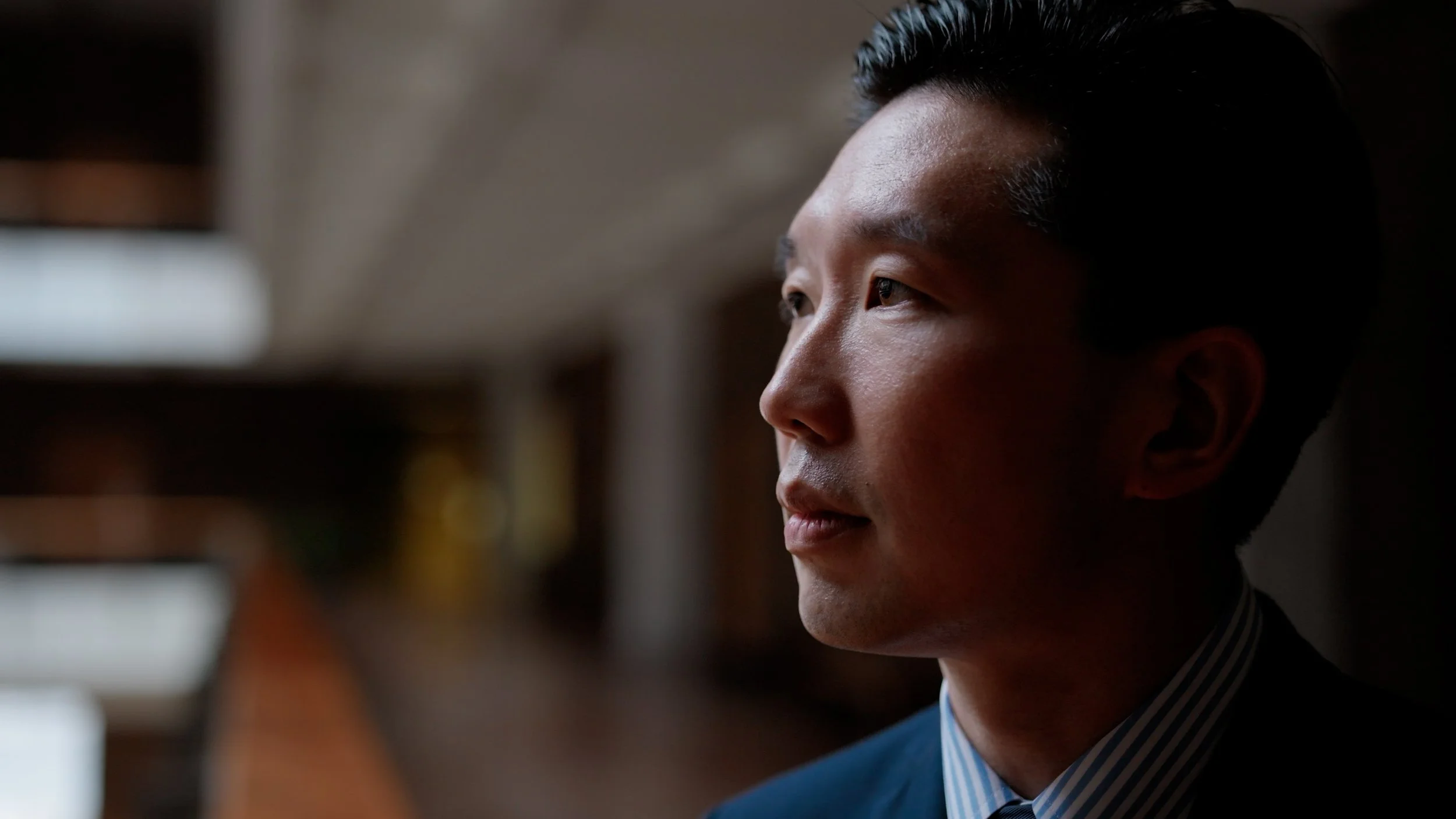 Man in a suit gazing out a window during an interview. Still from Priced Out of Paradise, a Hawaii housing documentary directed by Annie and Sam Menendez