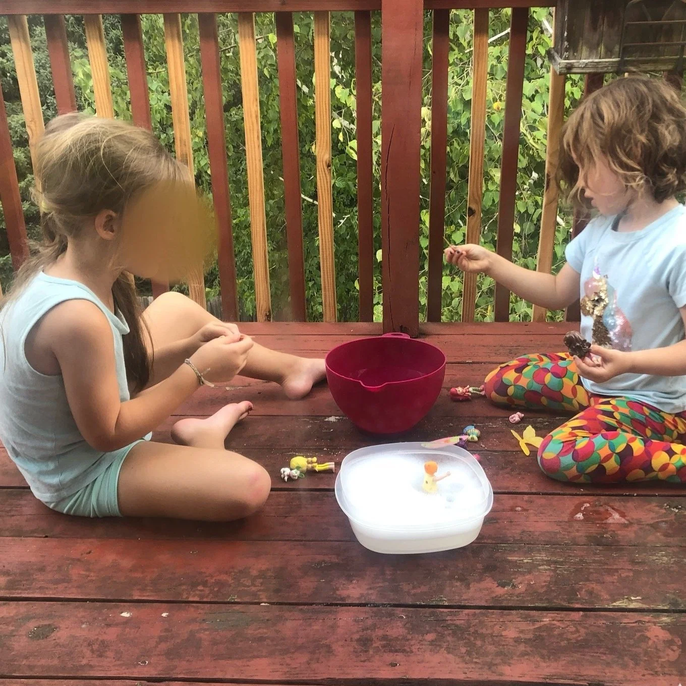 Two children are washing the bowls and toys with which they played with the kinetic sand.